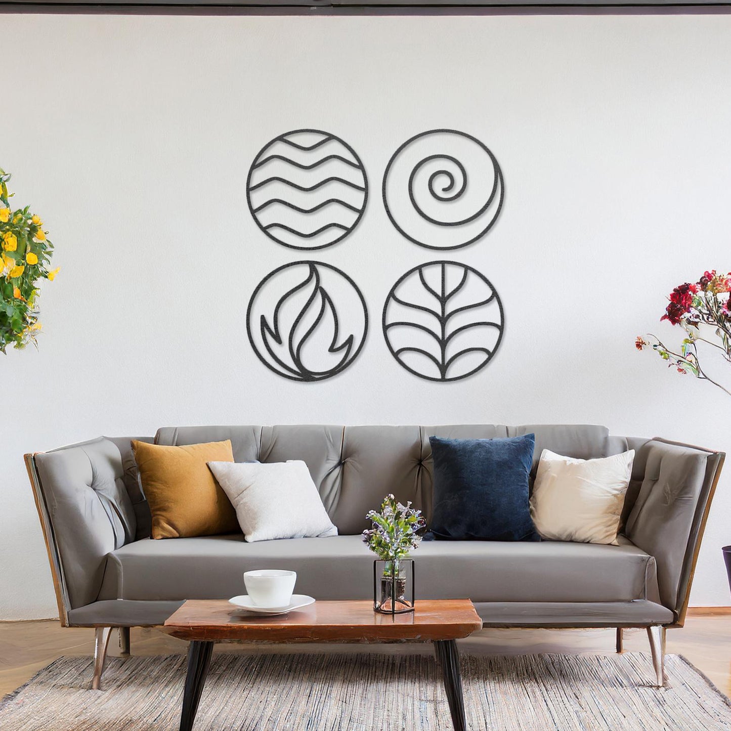 Wooden wall art set featuring four circular designs symbolising natural elements: waves for water, a spiral for air, flames for fire, and leaves for earth. Mounted on a neutral wall within modern decor, these minimalist designs evoke balance and harmony.