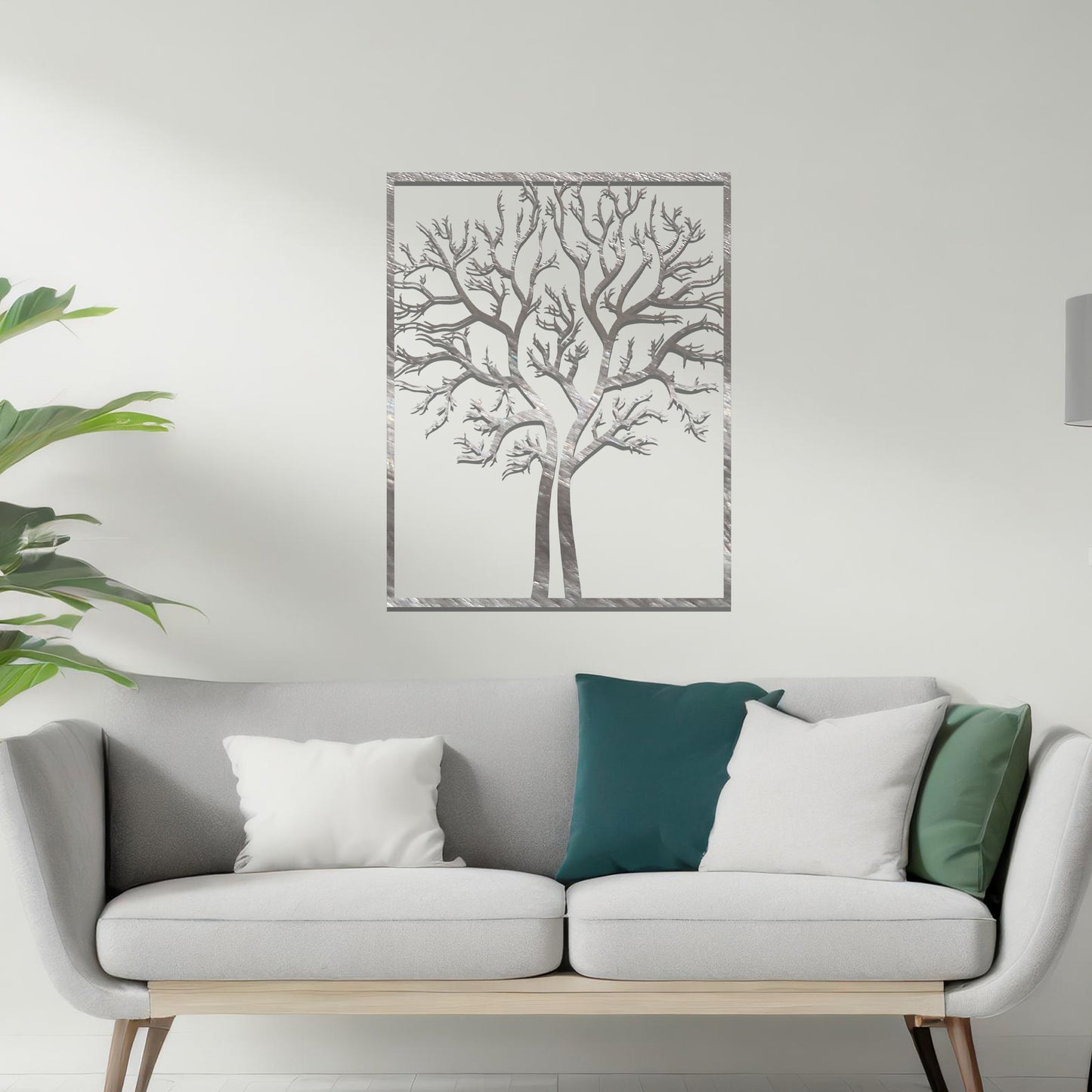 Metal wall art featuring a framed tree design with intricate, bare branches, crafted with precise laser-cut techniques, displayed on a neutral wall within modern decor.