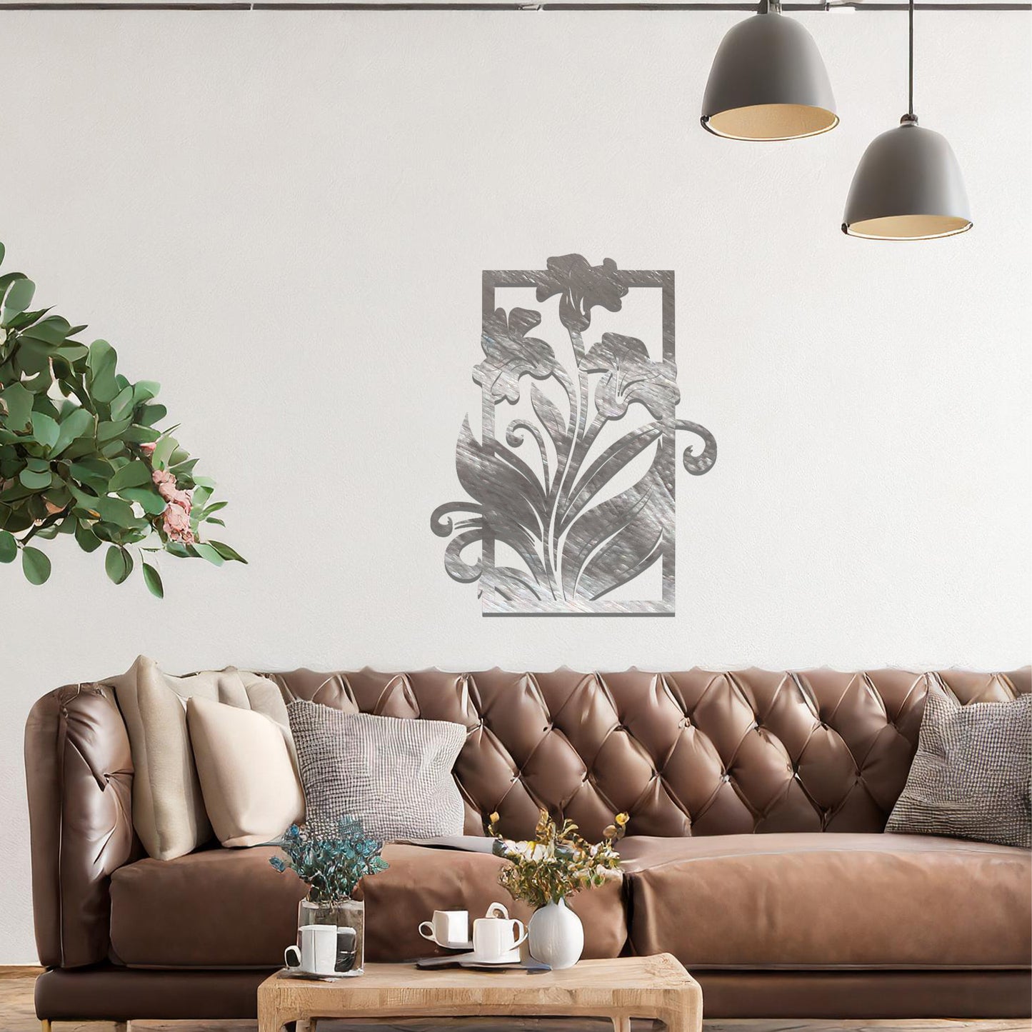 A metal wall art design featuring a graceful floral arrangement with flowers and curving leaves within a rectangular frame. The art is displayed on a neutral wall in a modern living room, enhancing the space with a touch of elegance and nature.
