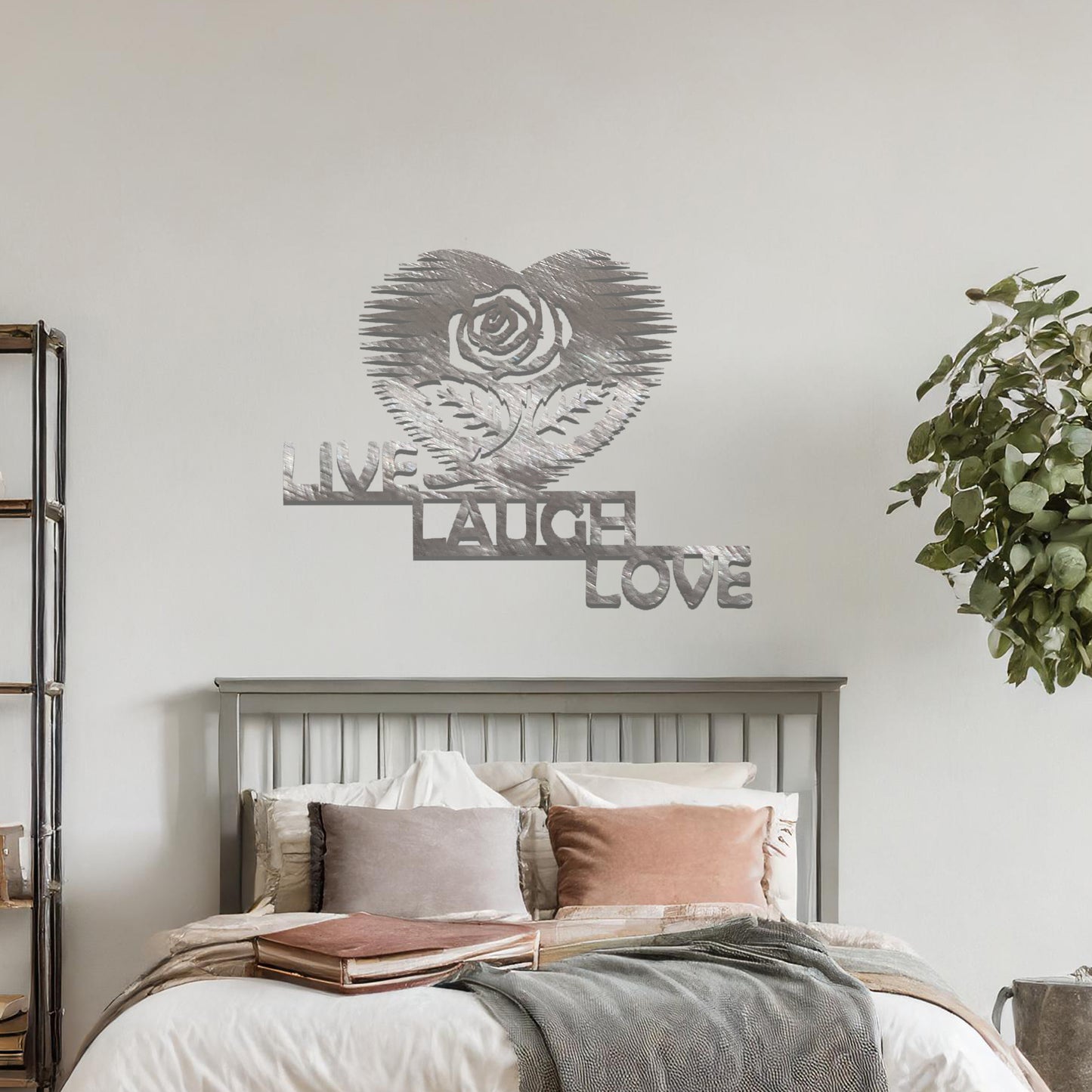 Metal wall art featuring the words "LIVE LAUGH LOVE" alongside a rose within a heart shape, with bold lines and intricate design. The art is displayed on a neutral wall within modern room decor, offering a stylish and motivational accent to the space.