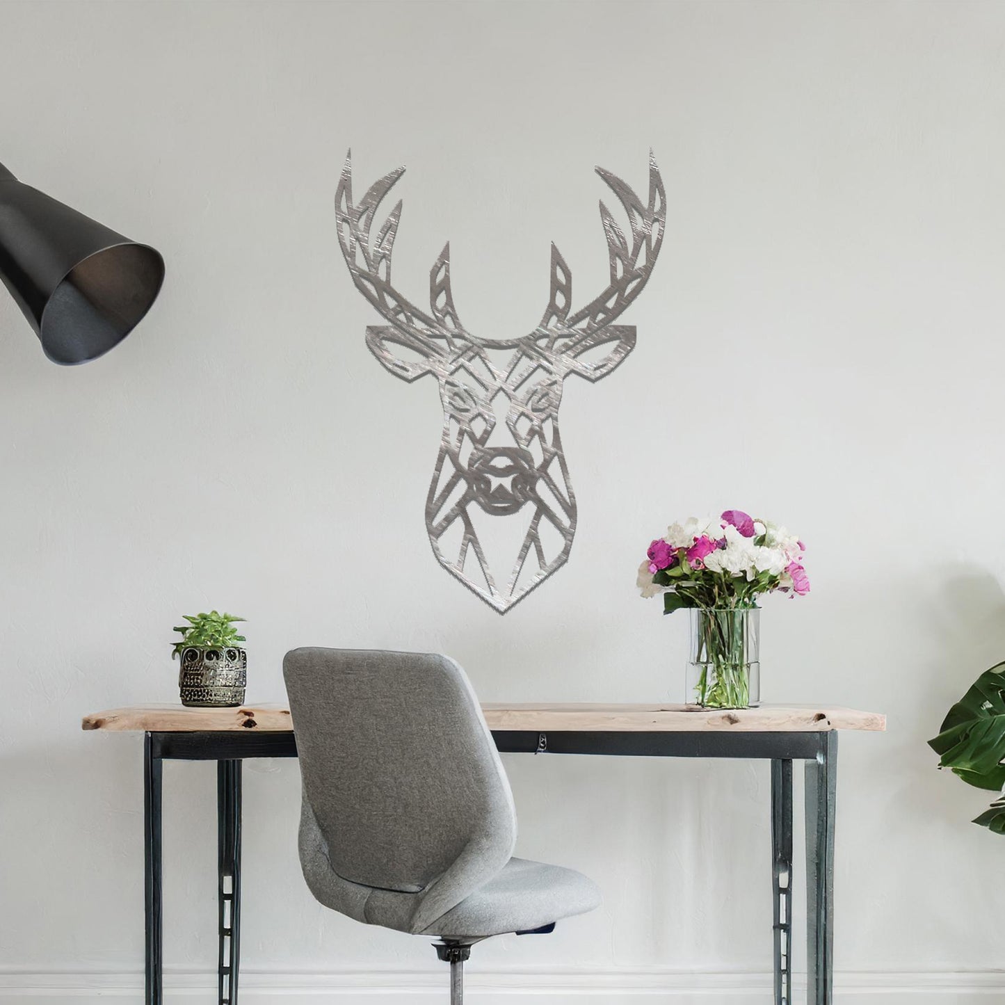 Metal wall art featuring a geometric deer head design with intricate detailing, crafted with precise laser-cut techniques, displayed on a neutral wall within modern decor.