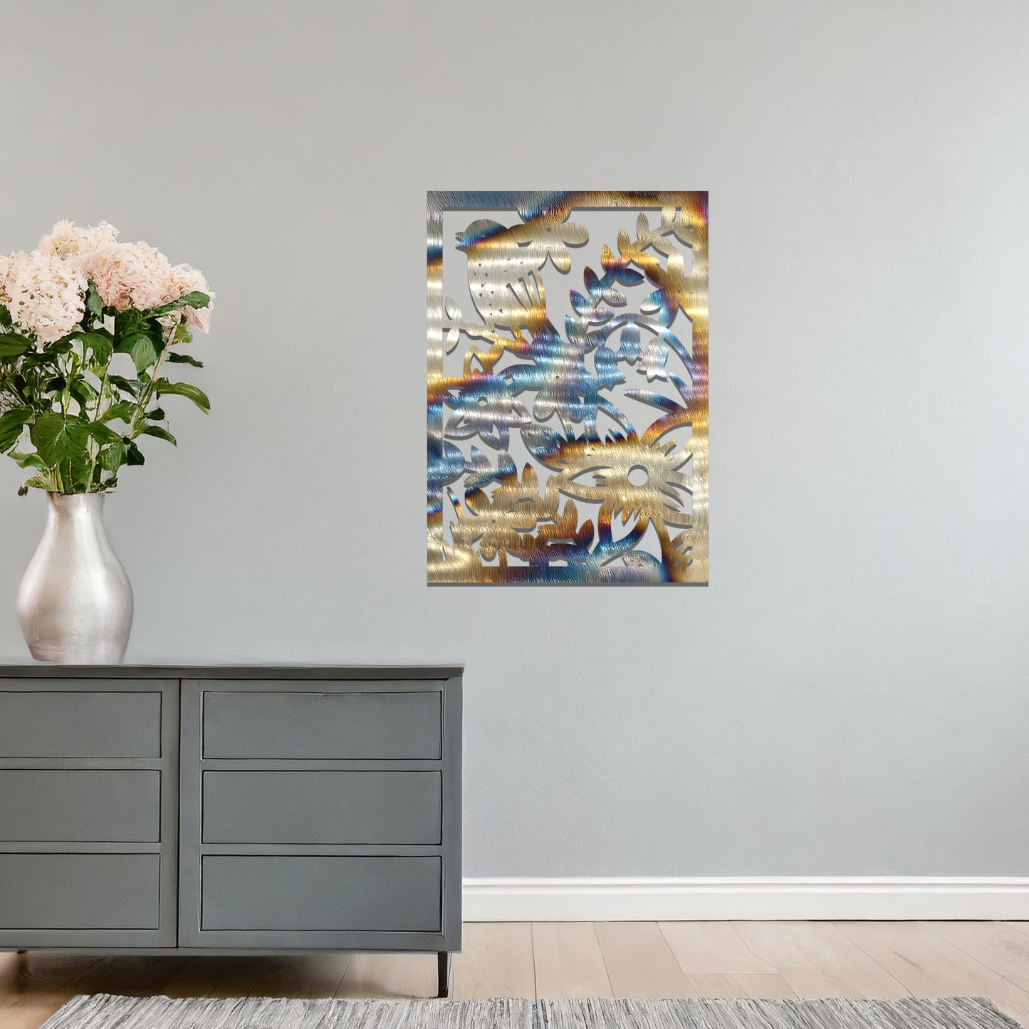 Metal wall art featuring a rectangular design with a bird perched amidst detailed floral and leafy patterns, mounted on a neutral wall within modern room decor. The intricate details and natural elements create a lively and elegant focal point.