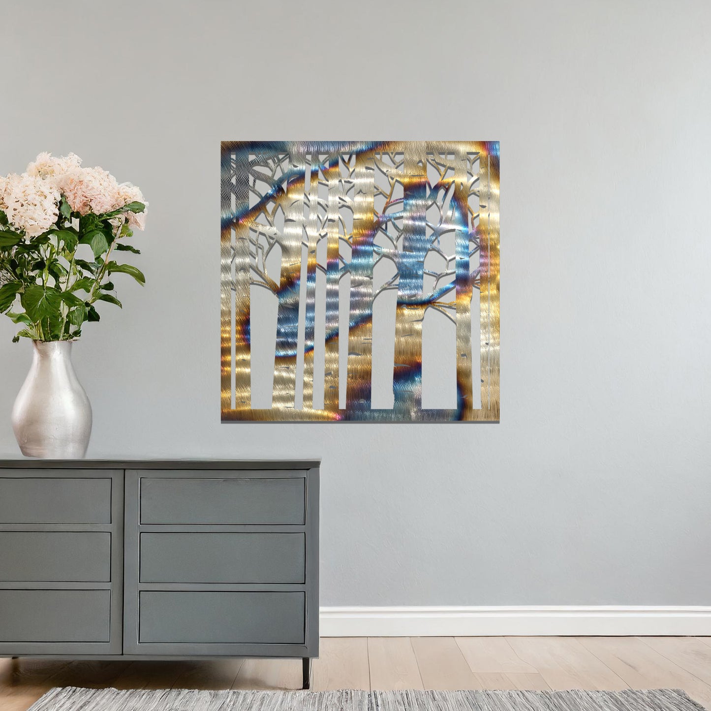 Metal wall art featuring a square design with a detailed forest of tall birch trees, mounted on a neutral wall within modern decor. The intricate silhouette adds a natural and elegant focal point to the room.