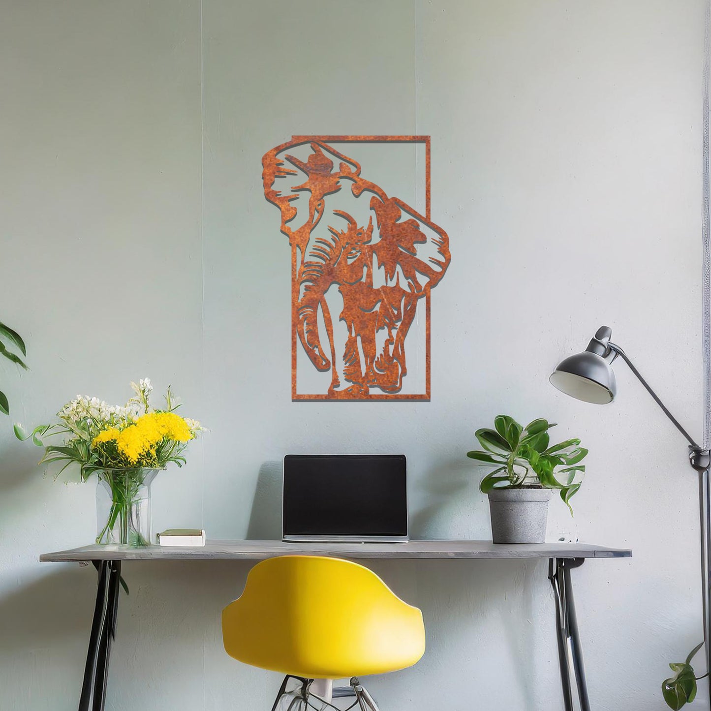 Metal wall art featuring a detailed silhouette of an elephant walking, framed by a rectangular border. The art is placed on a neutral wall in a modern office setting, adding a dynamic and nature-inspired element to the workspace decor.