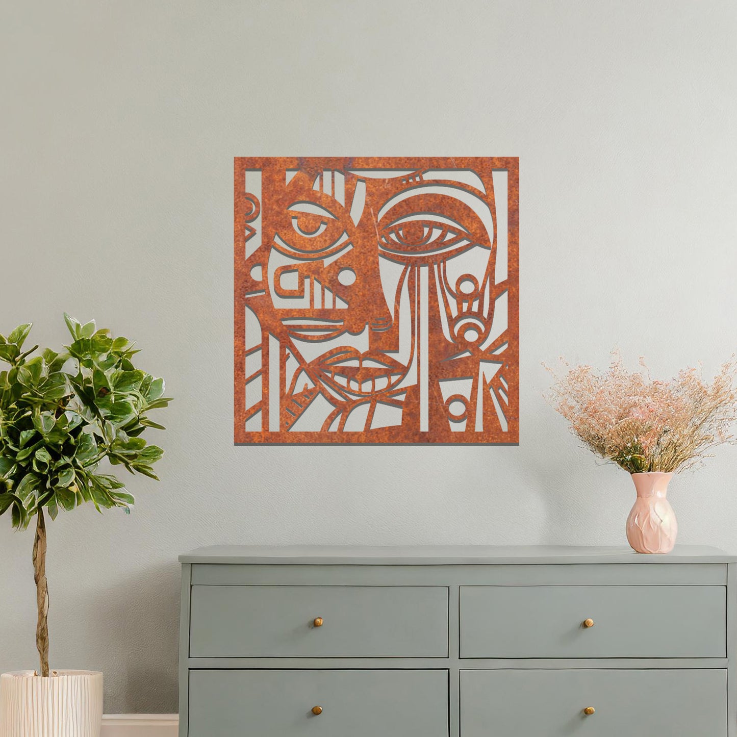 A metal wall art design featuring an abstract face with geometric shapes and sharp lines. The face's features are creatively outlined with strong contrasts, adding a modern, artistic touch to the space. The piece is displayed on a neutral wall, enhancing the room’s decor.