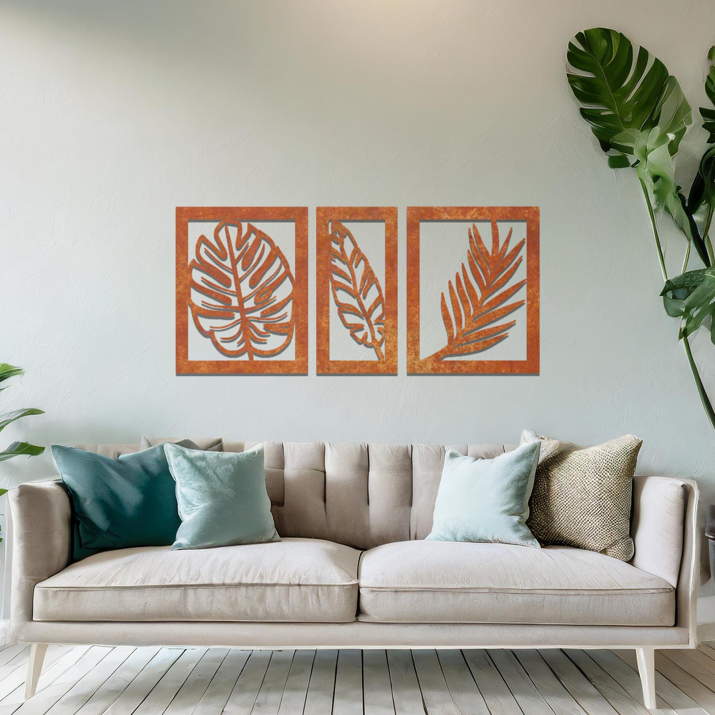 Metal wall art featuring a three-panel design with detailed leaf patterns, mounted on a neutral wall within modern decor. The organic motifs and rust finish create a natural, earthy focal point, enhancing the room's aesthetic.