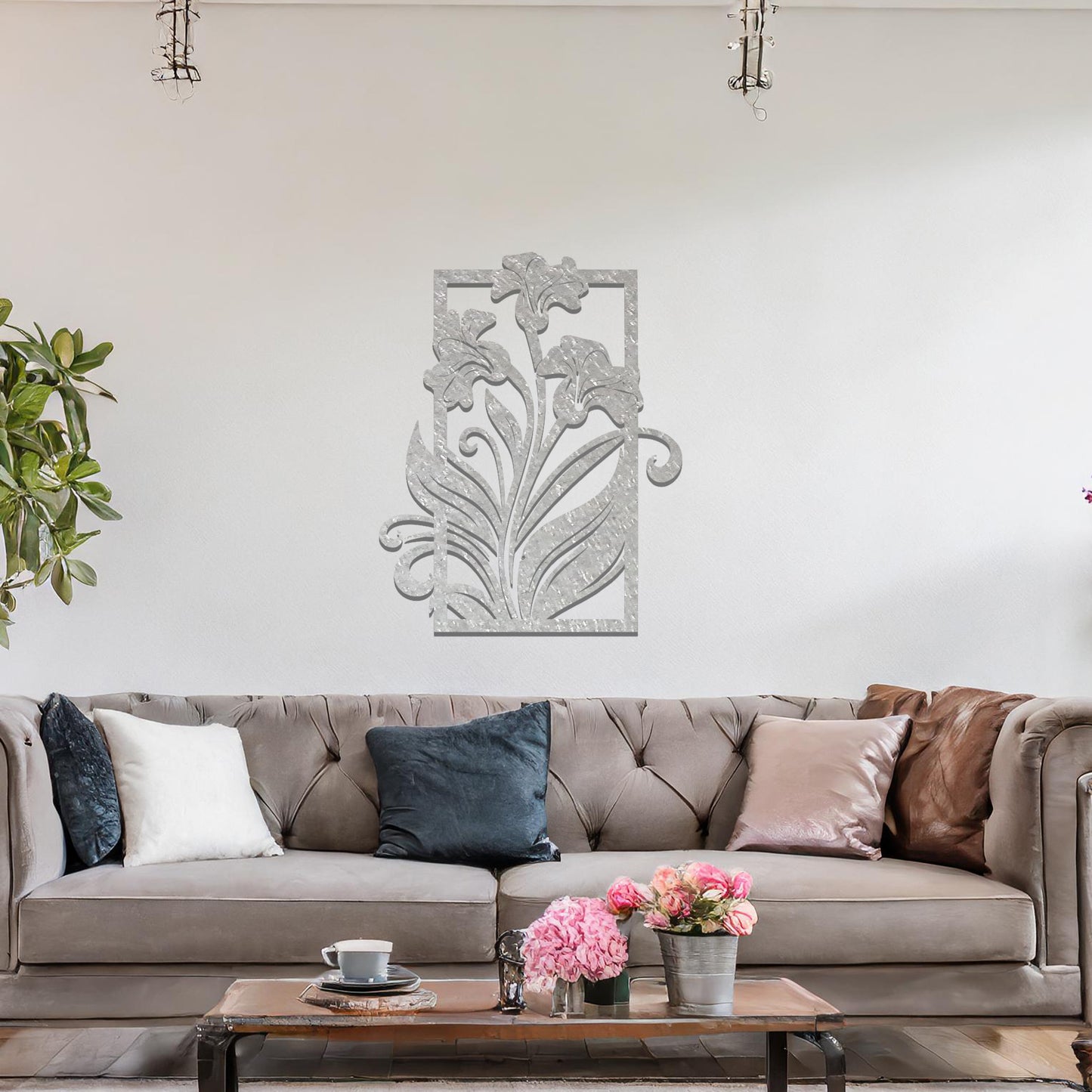 A metal wall art design featuring a graceful floral arrangement with flowers and curving leaves within a rectangular frame. The art is displayed on a neutral wall in a modern living room, enhancing the space with a touch of elegance and nature.
