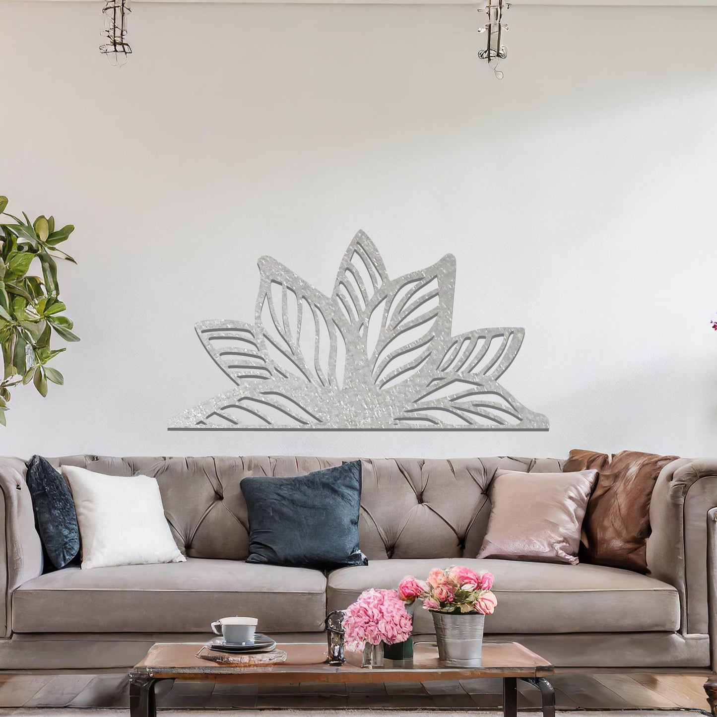 A beautifully intricate metal wall art design featuring a large, stylized lotus flower with detailed, flowing leaves. The art piece is placed on a neutral wall within a modern living room, adding elegance and natural beauty to the space.