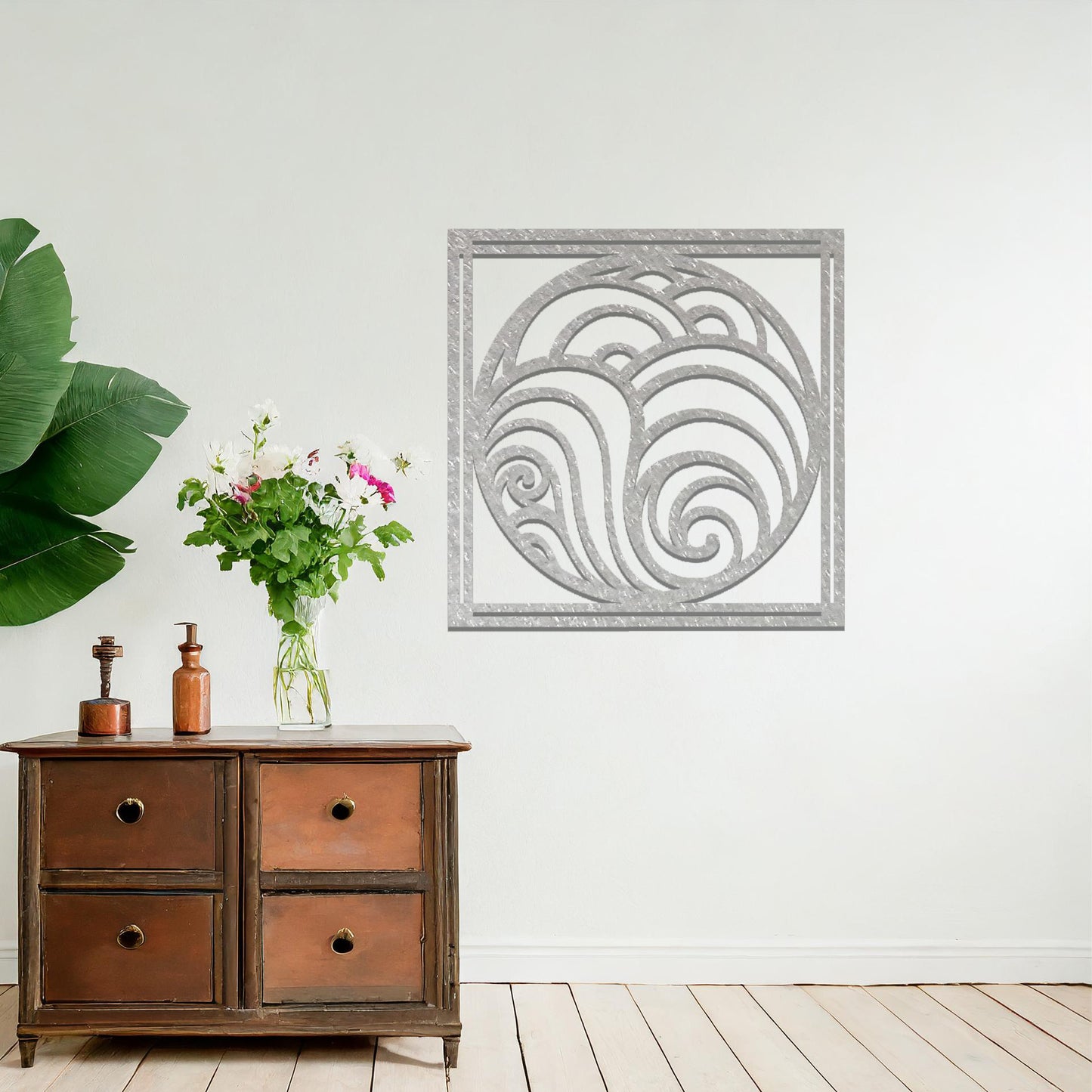 Metal wall art featuring a square design with swirling wave patterns inside a circular frame, mounted on a neutral wall within modern decor. The flowing lines and fluid shapes create a peaceful and dynamic focal point, enhancing the space.