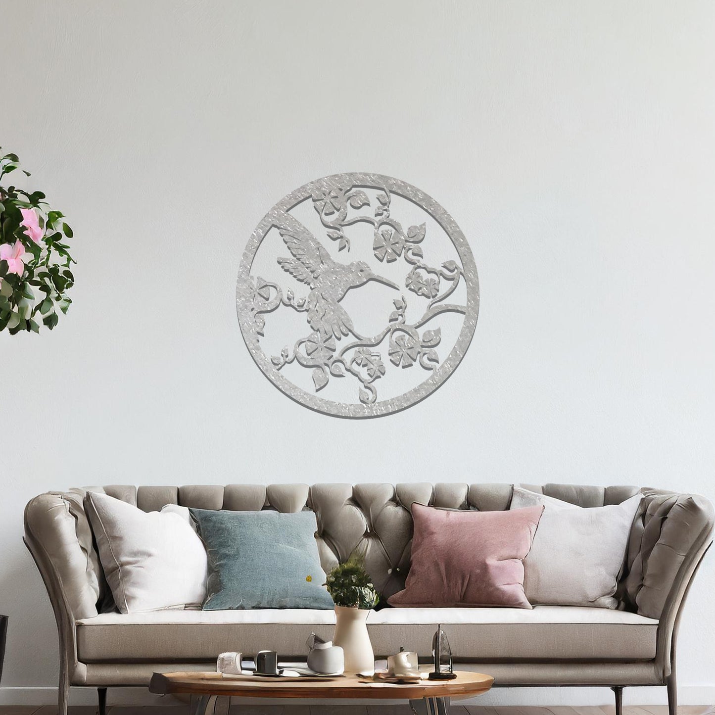 Metal wall art featuring a bird perched on floral vines in a circular design. The intricate patterns of the leaves and branches are beautifully balanced, creating a harmonious look. The art is placed on a neutral wall within modern room decor.