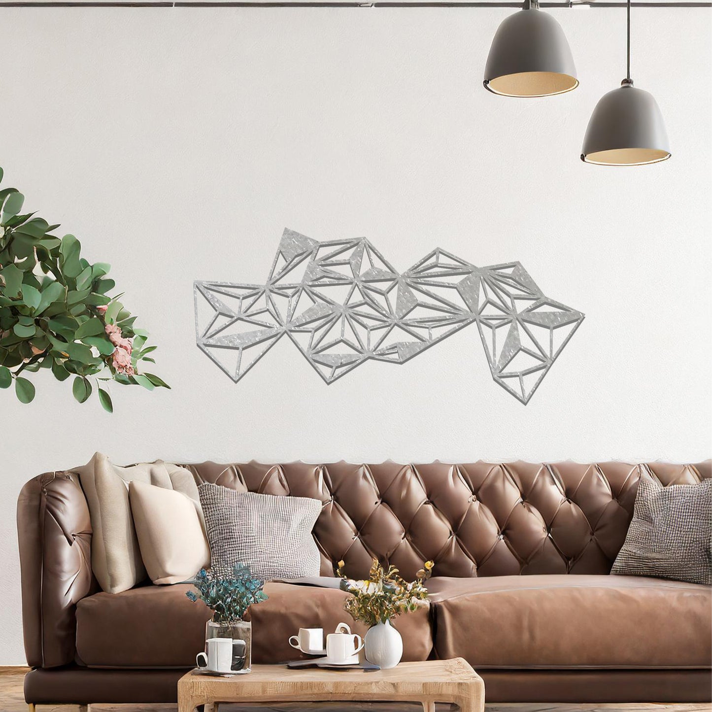 Metal wall art featuring an abstract geometric design with multiple interconnected triangular shapes, creating a dynamic, faceted pattern. The art is placed on a neutral wall within a modern room, complementing the vibrant decor with plants and furniture.