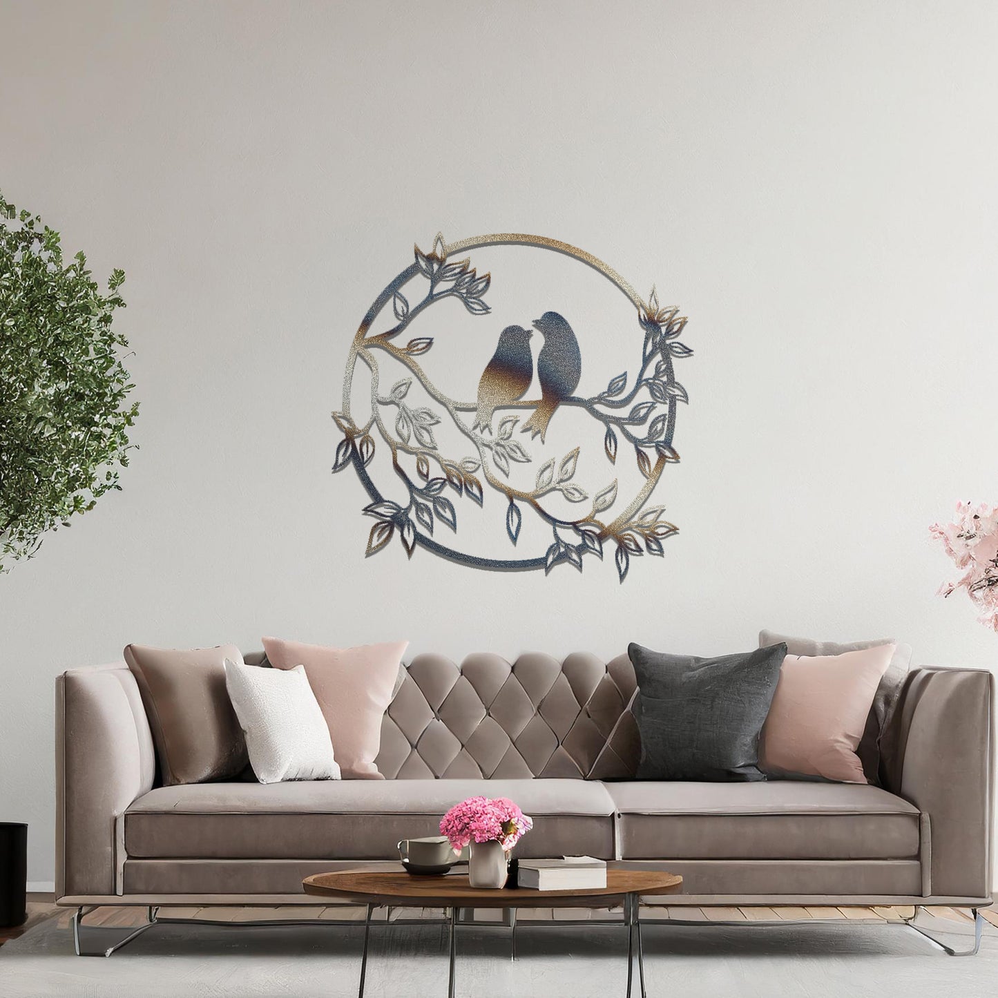 Metal wall art featuring a circular design with two birds perched on a branch surrounded by intricate leaves, adding a charming focal point to a beautifully styled living space.