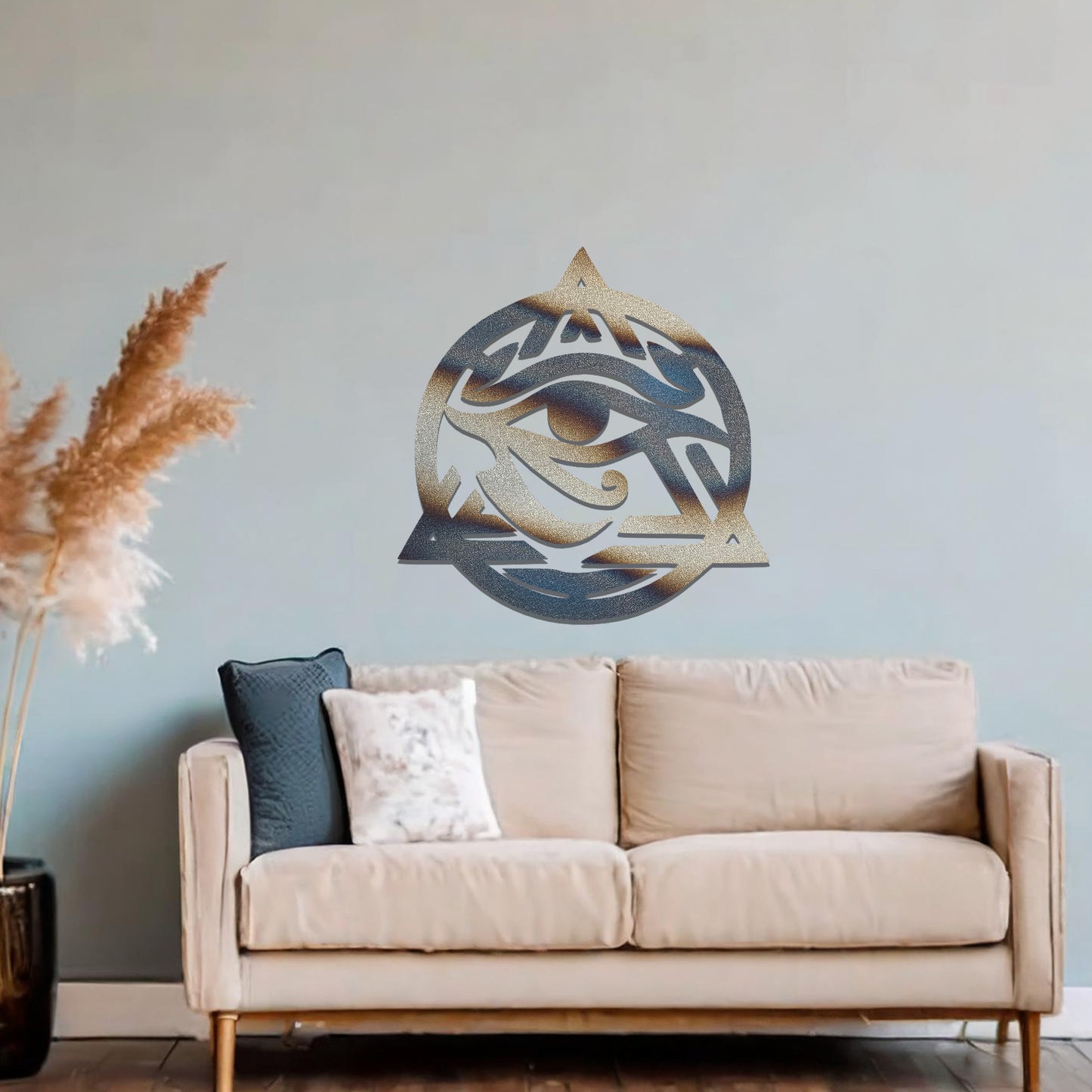 Metal wall art featuring an intricate design of the Eye of Horus, enclosed within a geometric triangle and circle. The artwork is placed on a neutral wall in a modern living room setting, adding to the contemporary decor.