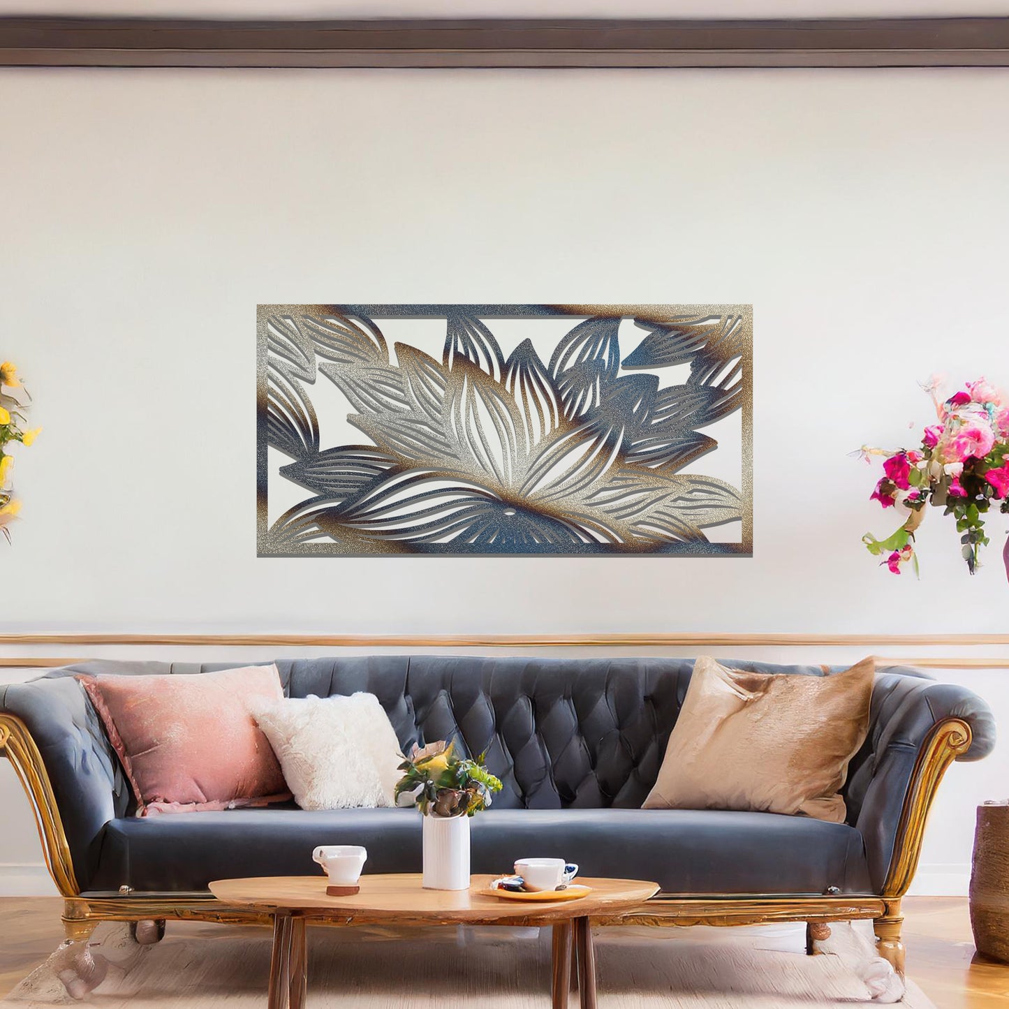 A metal wall art design showcasing a lotus flower with detailed, flowing petals. The design is framed within a rectangular shape. The art is displayed on a neutral wall within a modern living room setting, complementing the room's elegant decor.