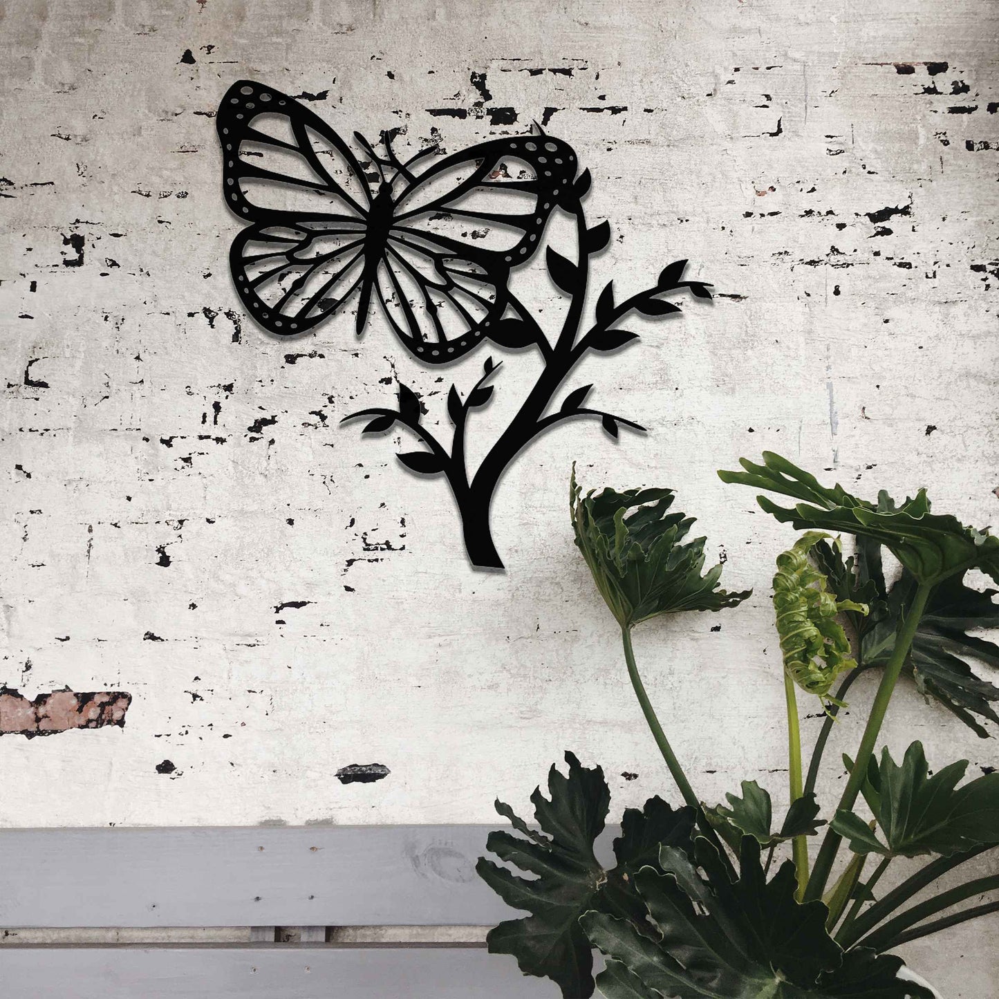 Metal garden decoration featuring a butterfly resting on a leafy branch, crafted with intricate detailing to bring a touch of nature-inspired elegance and charm to outdoor walls or garden settings.