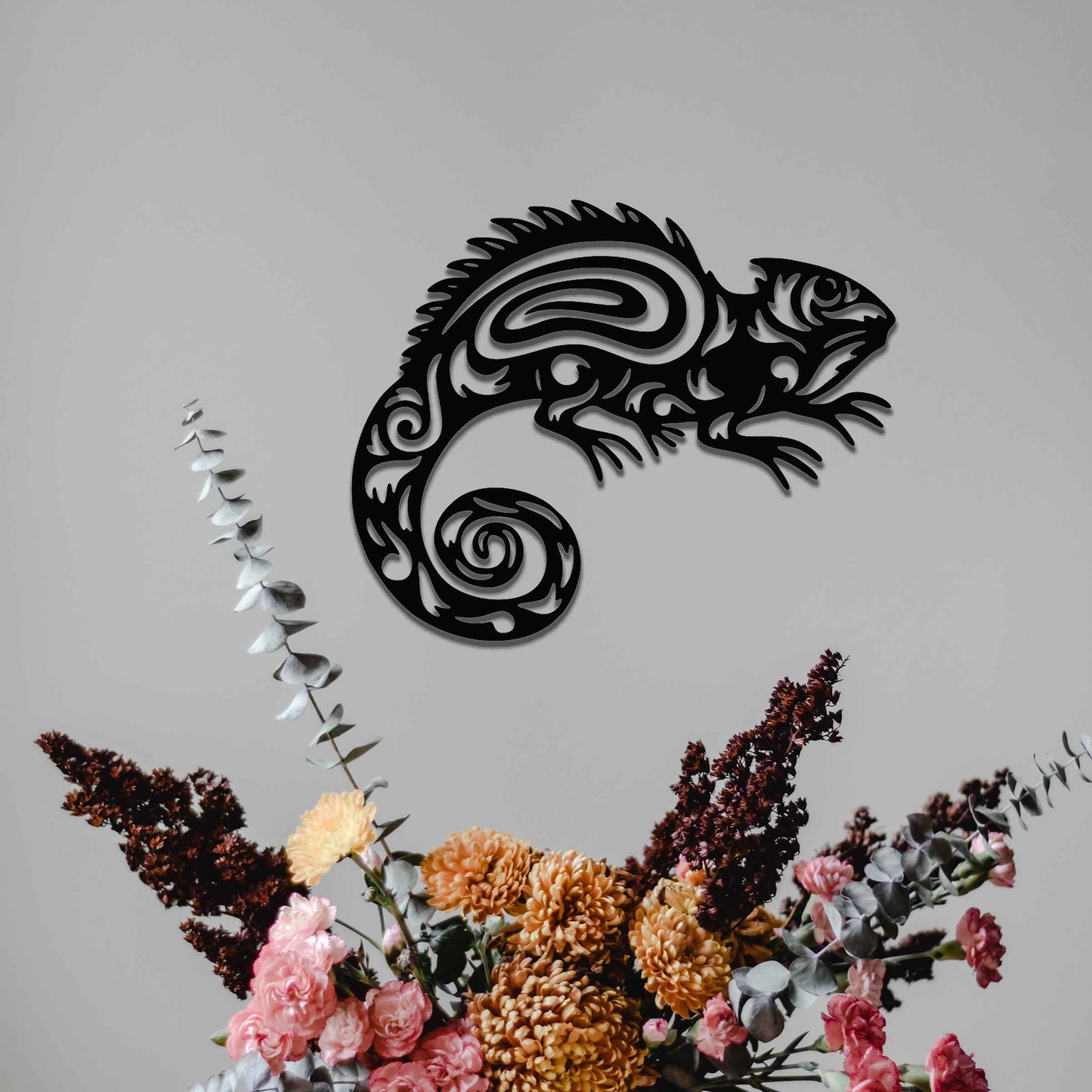 Metal wall decoration featuring a chameleon design with intricate tribal-inspired cutouts, adding an exotic and artistic touch to indoor spaces, displayed on a neutral wall in modern decor.