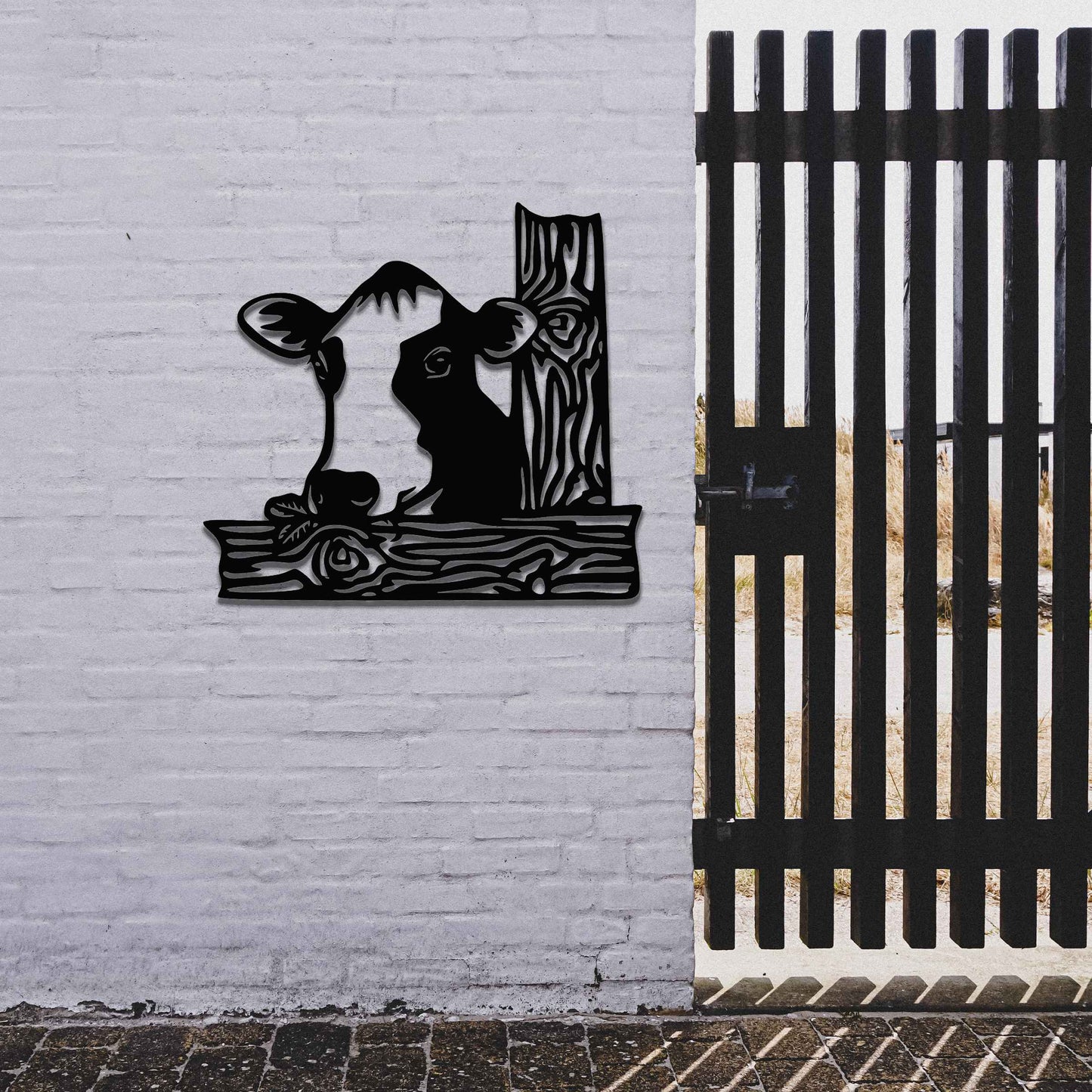 The design features a cow's head peeking over a wooden fence. The cow is drawn with distinct lines, giving it a playful and curious look. The stylized wooden posts complement the cow’s design, adding depth and structure.