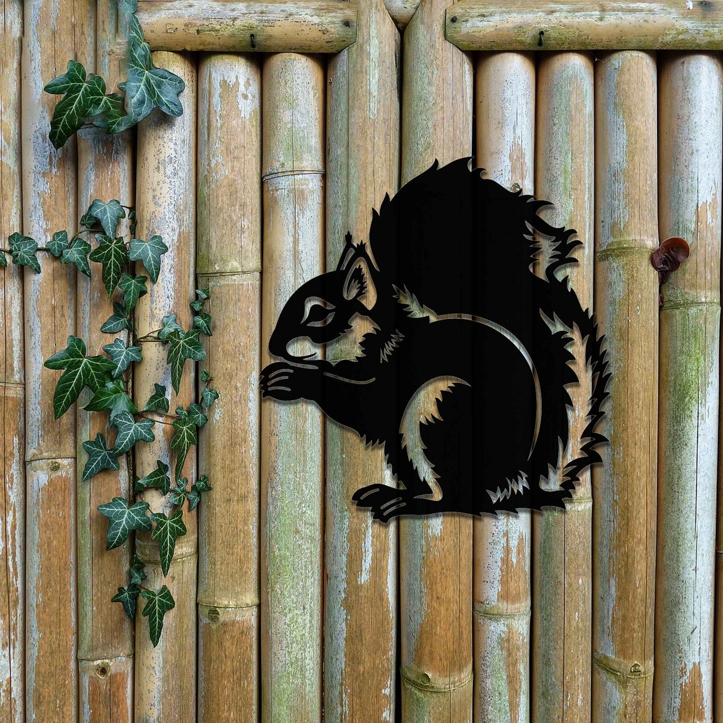 Metal garden decoration featuring a squirrel design with intricate cutout details, adding a whimsical and rustic charm to outdoor walls, blending seamlessly with natural garden surroundings.