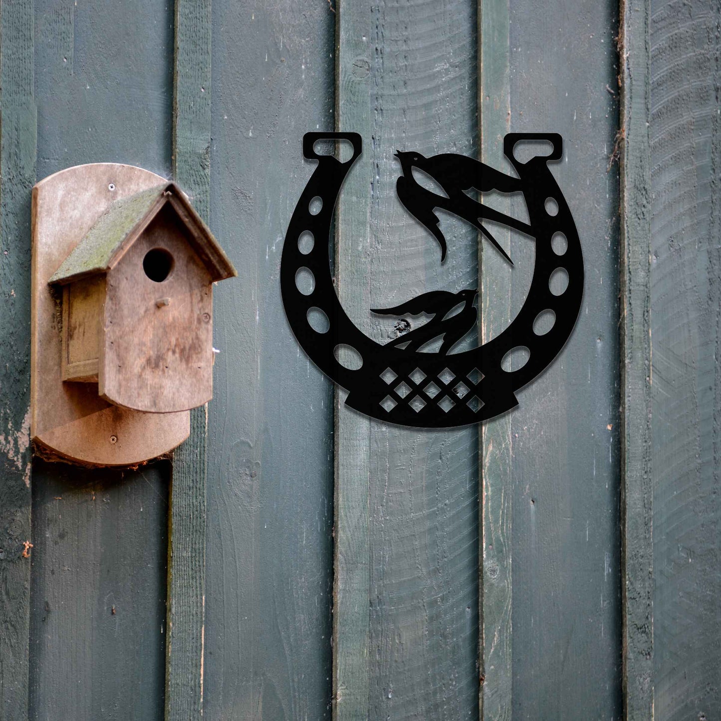 Metal garden decoration featuring two swallows perched within a horseshoe design, crafted with intricate detailing to symbolise luck and harmony, adding a rustic and charming touch to outdoor walls or fences.