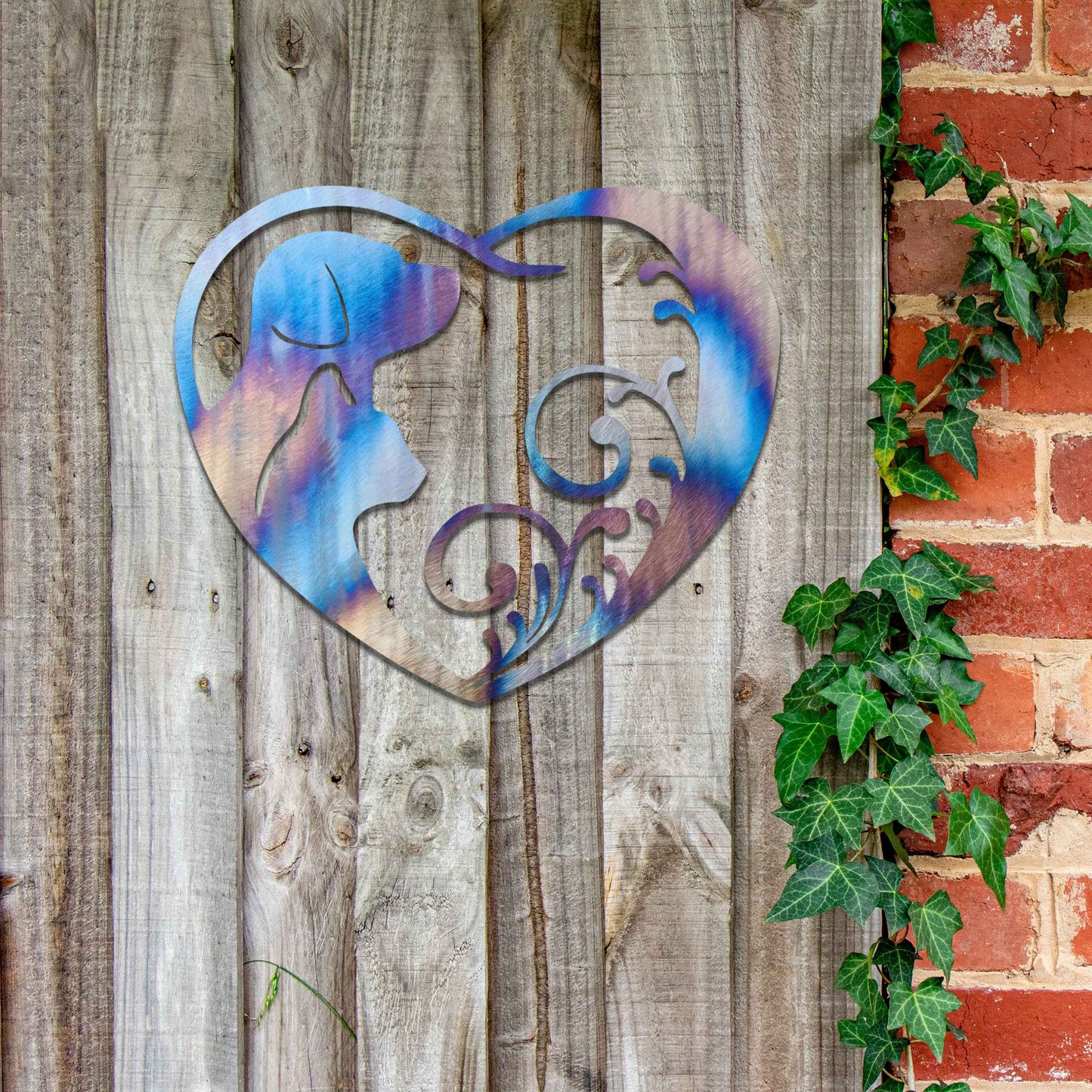 Metal garden decoration featuring a heart-shaped design with silhouettes of a dog and cat intertwined with elegant scrollwork, symbolising love for pets and adding a decorative charm to outdoor walls or garden spaces.