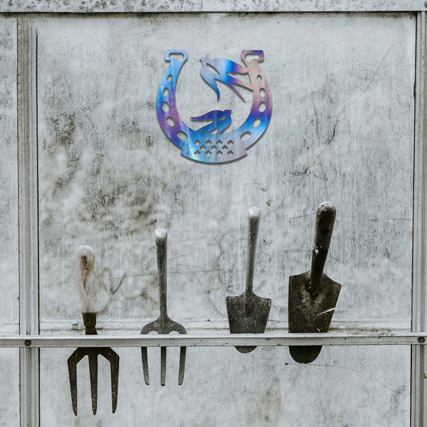 Metal garden decoration featuring two swallows perched within a horseshoe design, crafted with intricate detailing to symbolise luck and harmony, adding a rustic and charming touch to outdoor walls or fences.