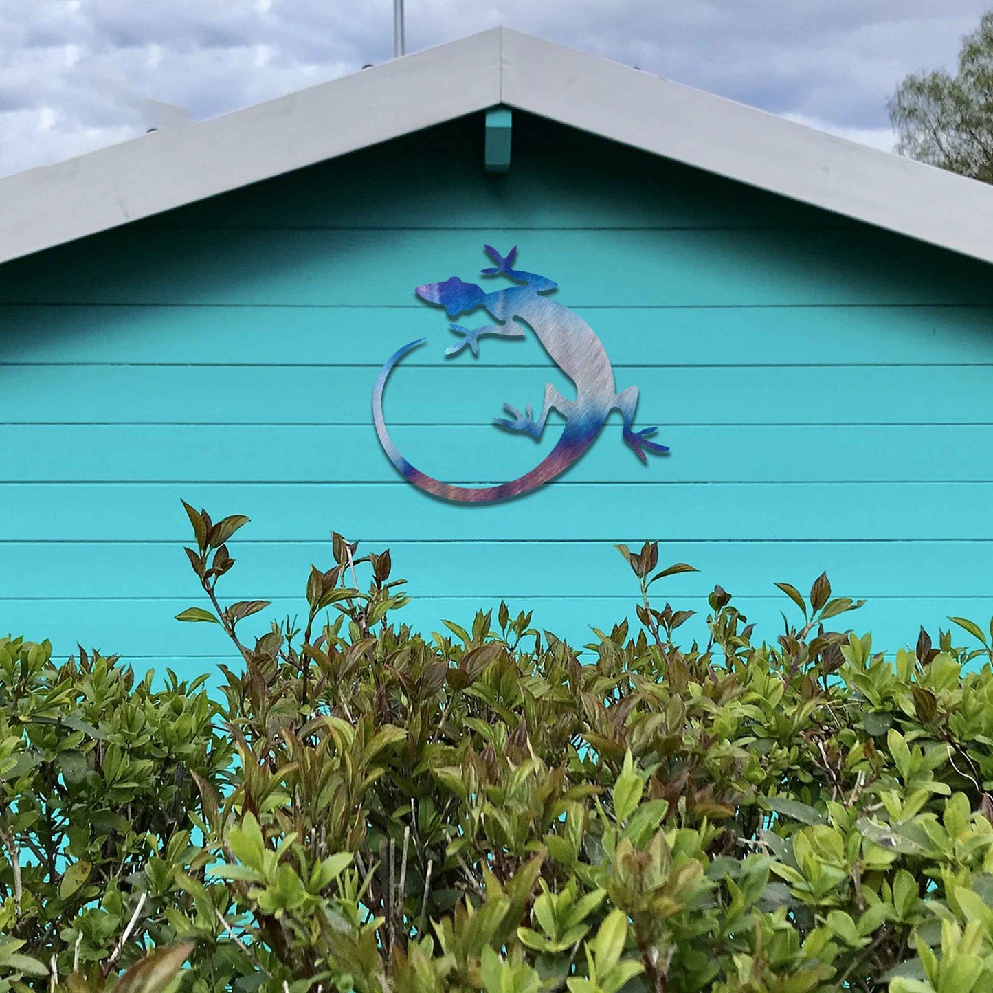 Metal garden decoration featuring a gecko silhouette design with a curved tail, adding a sleek and contemporary accent to outdoor walls, seamlessly complementing rustic and minimalist spaces.