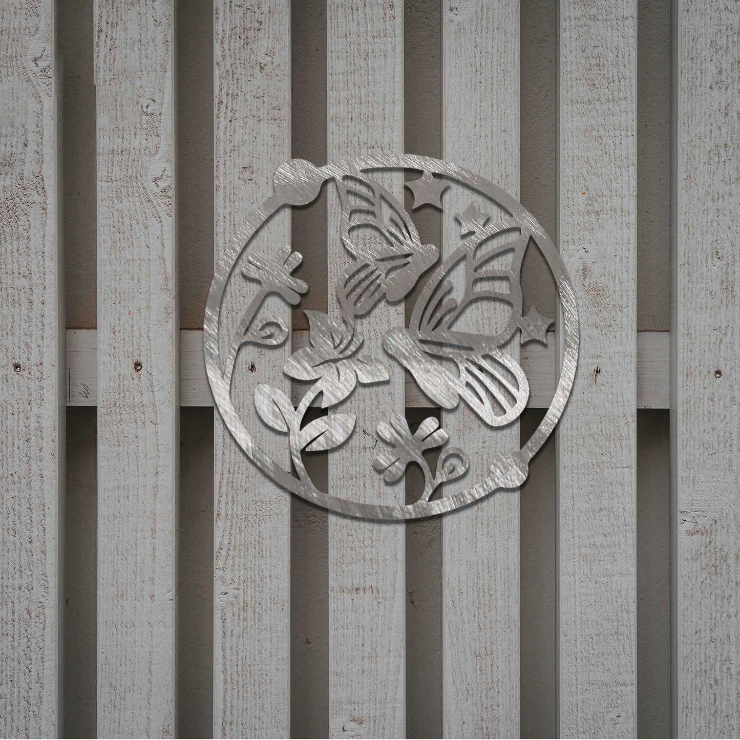 Metal garden decoration featuring a circular design with butterflies, flowers, and stars, crafted with a rustic finish, adding a whimsical and nature-inspired charm to outdoor walls or fences.