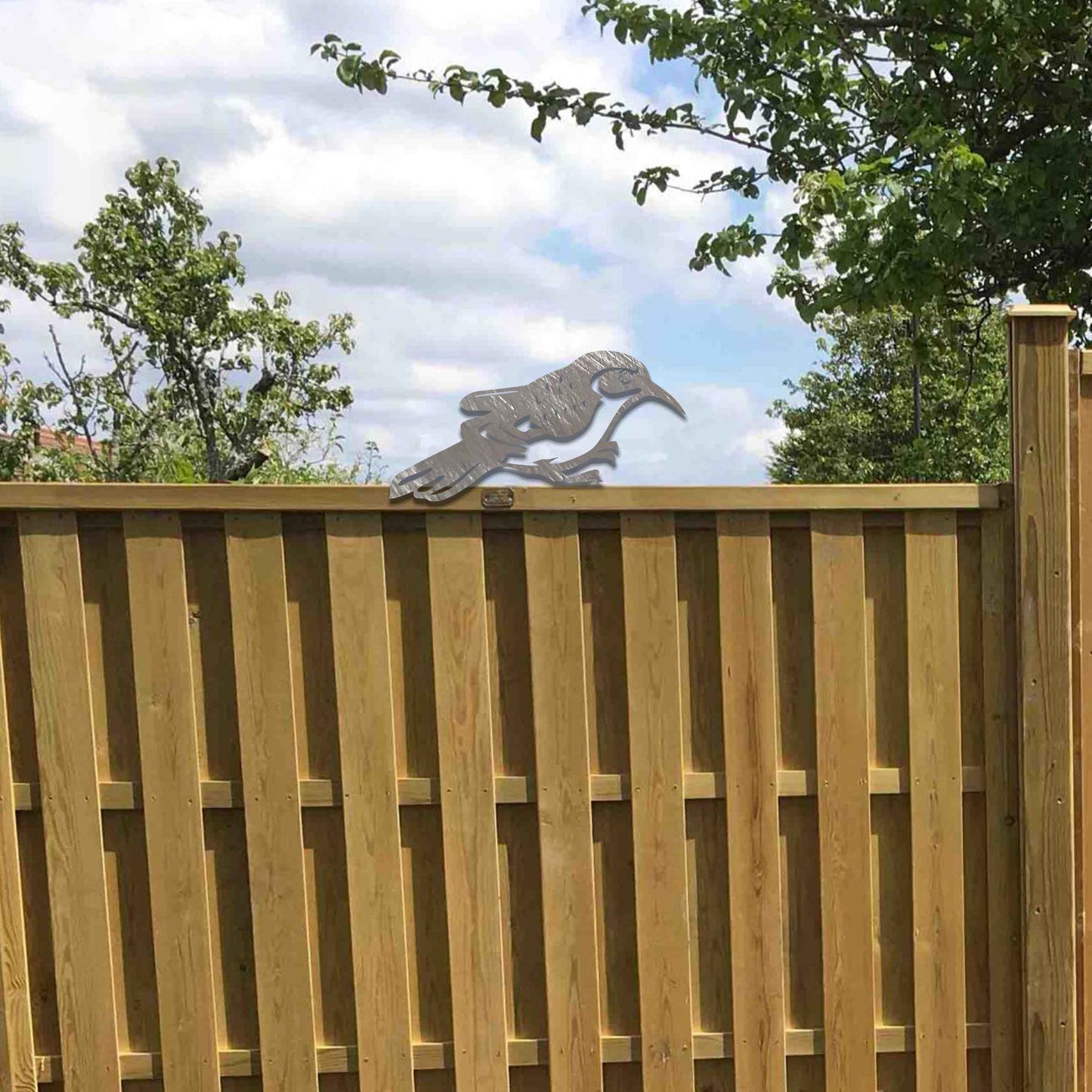 Metal garden decoration featuring a bird silhouette with intricate cutout details, adding a sleek and modern touch to outdoor spaces, designed to sit gracefully on fence posts or wooden beams.