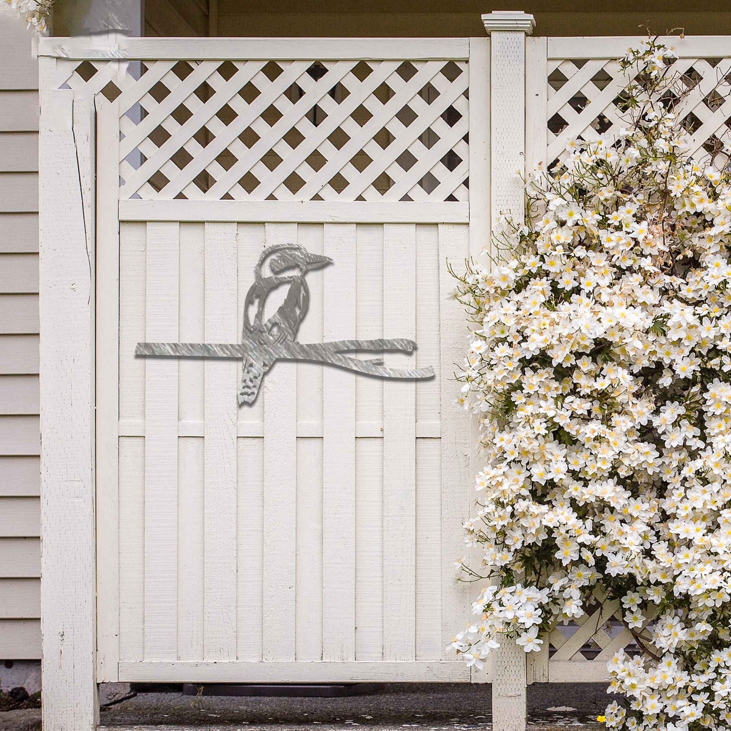 Metal garden decoration featuring a kingfisher perched on a branch with intricate cutout details and a rustic finish, designed to enhance walls or fences, adding a natural and elegant touch to outdoor spaces.