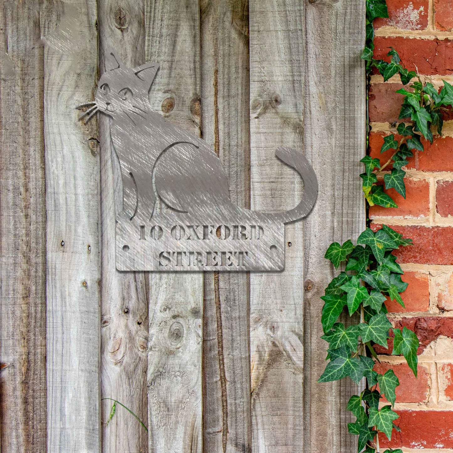 Metal garden decoration featuring a sleek sitting cat silhouette with a personalised address plaque, combining practicality with artistic charm for outdoor walls, fences, or gates.