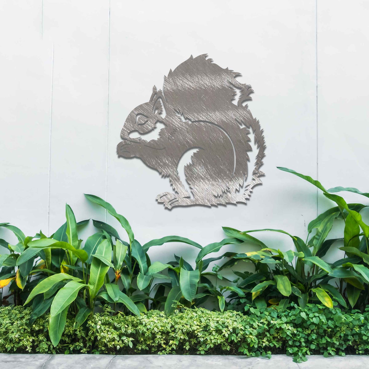 Metal garden decoration featuring a squirrel design with intricate cutout details, adding a whimsical and rustic charm to outdoor walls, blending seamlessly with natural garden surroundings.