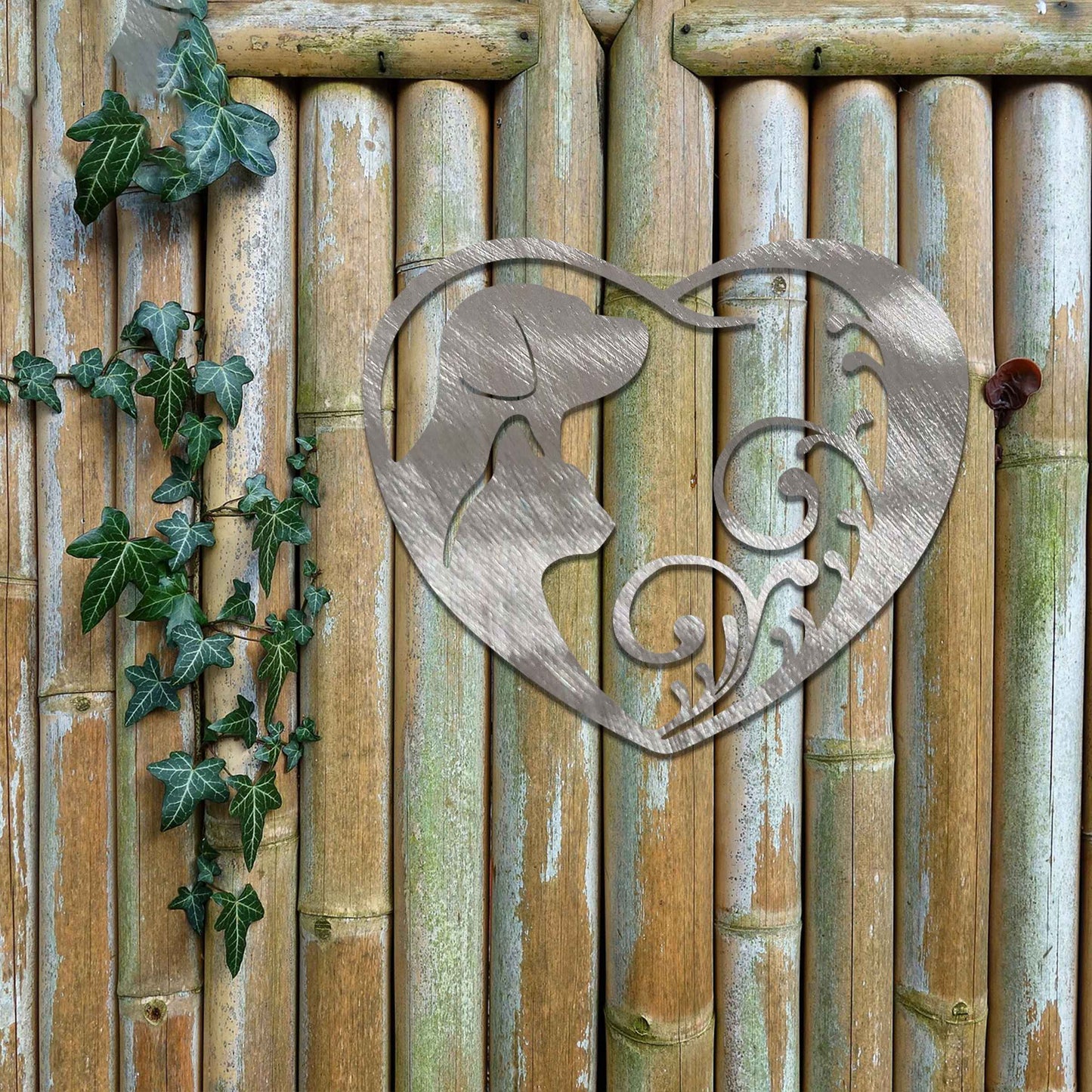 Metal garden decoration featuring a heart-shaped design with silhouettes of a dog and cat intertwined with elegant scrollwork, symbolising love for pets and adding a decorative charm to outdoor walls or garden spaces.