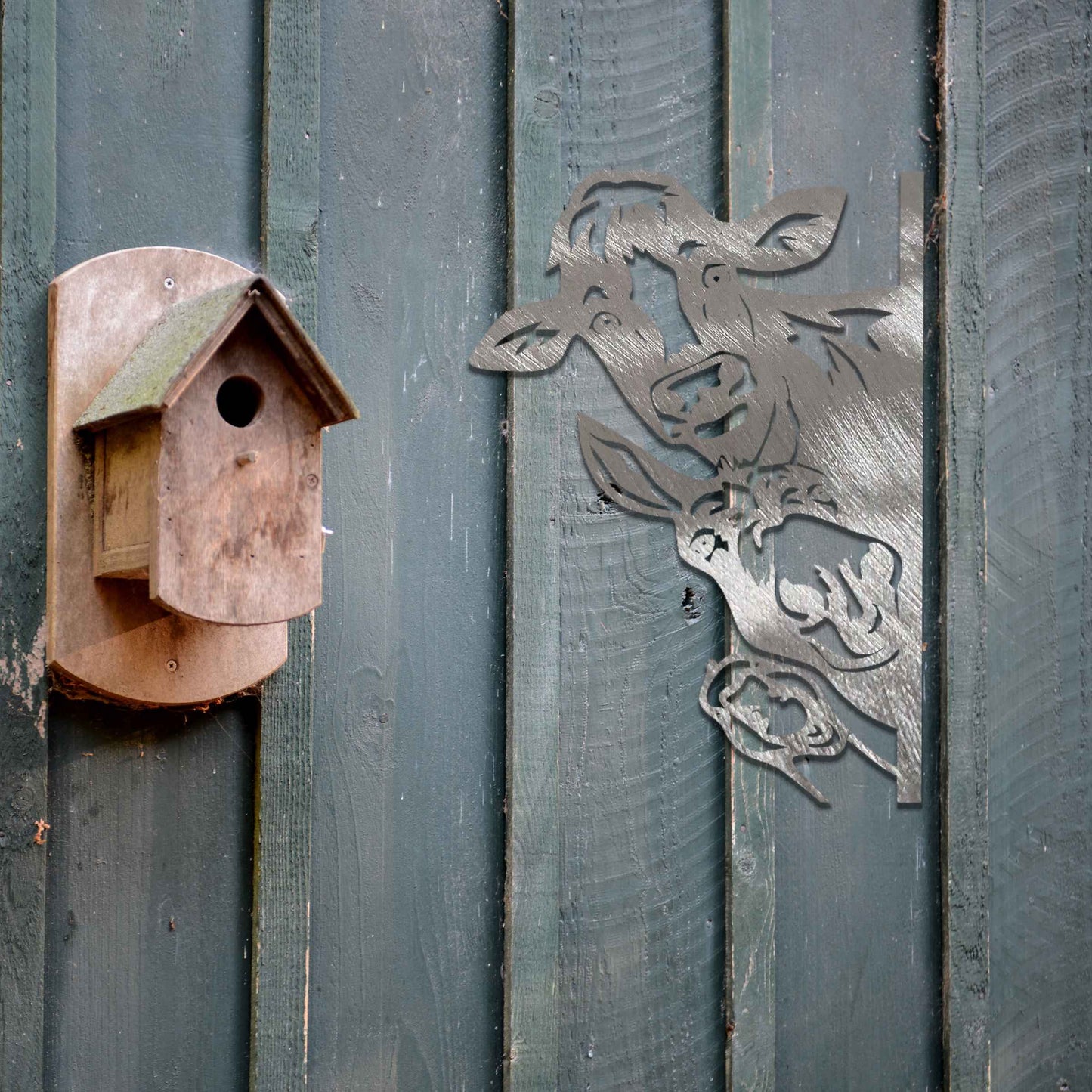 Metal decoration featuring a cow, a donkey, and a goose peeking around a vertical edge, crafted with intricate cutout details and a rustic finish, adding a whimsical and rustic charm to outdoor or garden spaces.