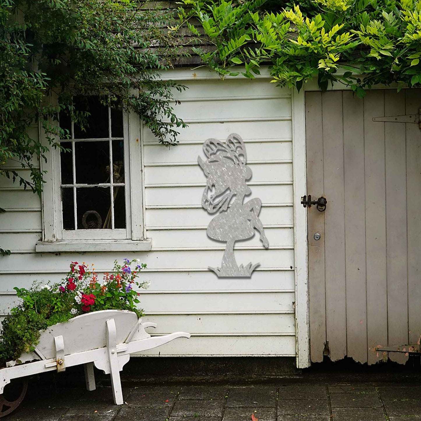 This image features a fairy perched on a mushroom, its silhouette highlighted by intricate wings. The whimsical design is enhanced by the playful stance of the fairy, adding a touch of enchantment to any garden or outdoor space.