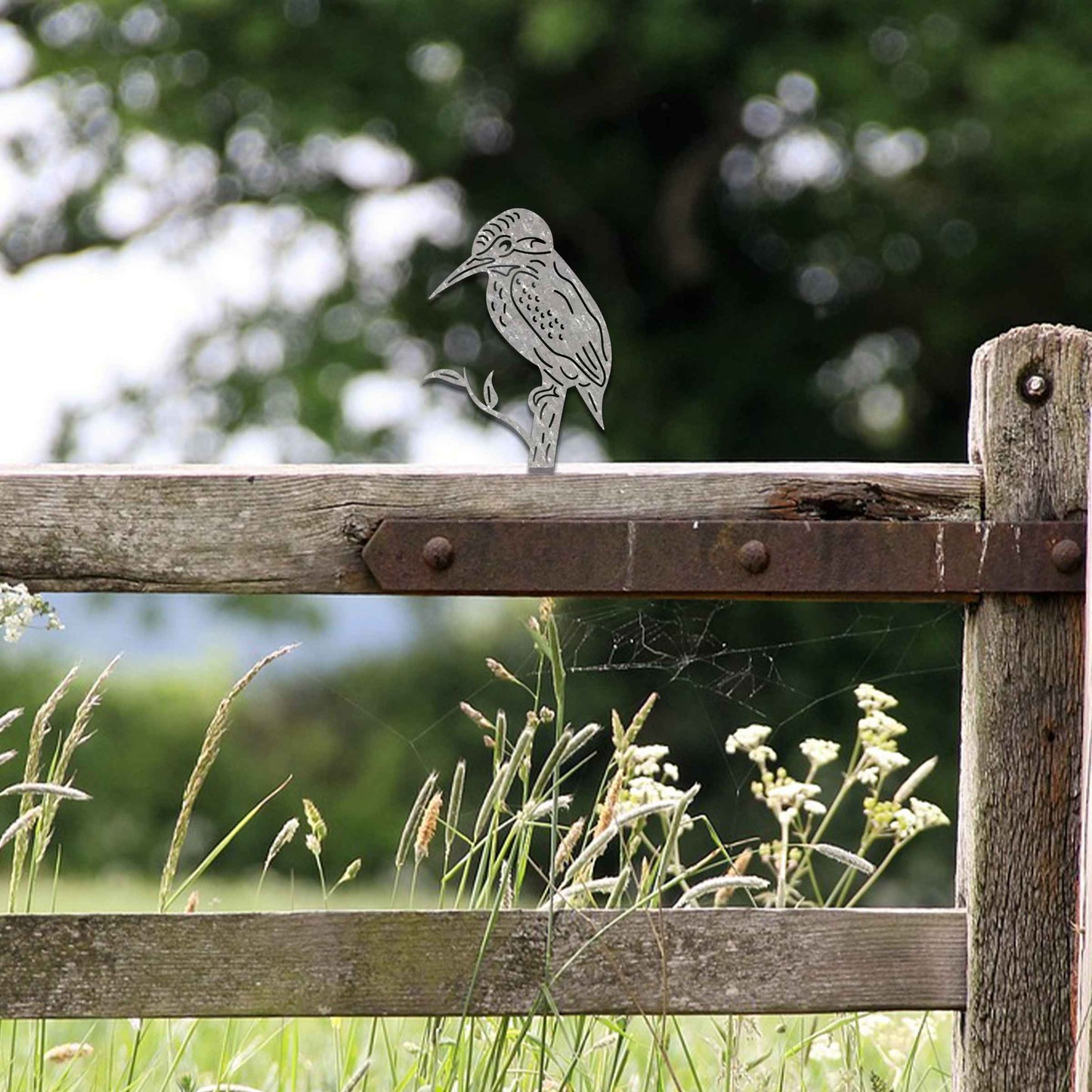 Metal garden decoration featuring a kingfisher silhouette perched on a branch, crafted with a rustic finish, designed to sit atop fences or garden posts, adding a natural and artistic accent to outdoor spaces.