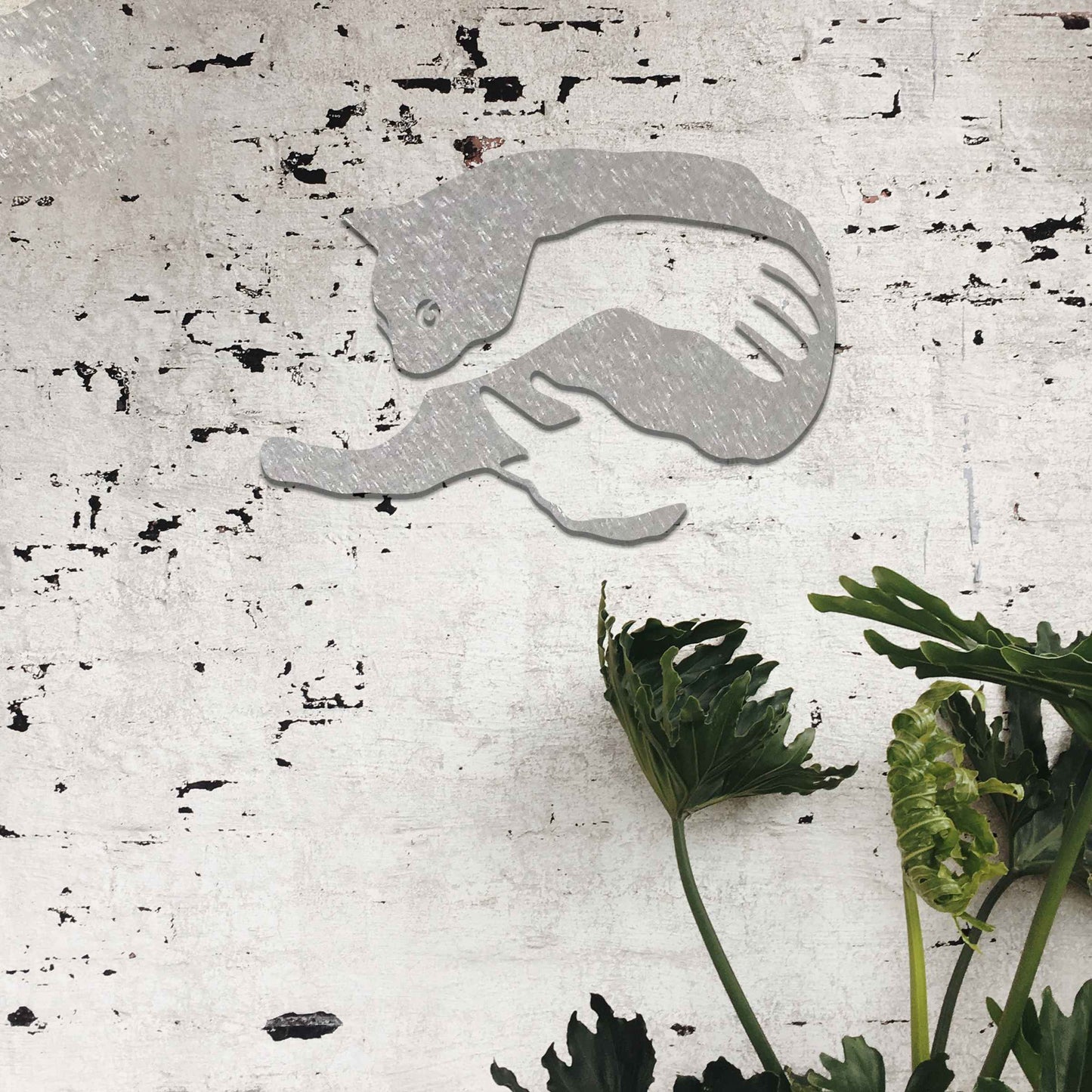 Metal wall art featuring a minimalist silhouette of a cat being gently held by a pair of hands. A striking and heartwarming design that adds an artistic and cosy touch to any modern or contemporary space.