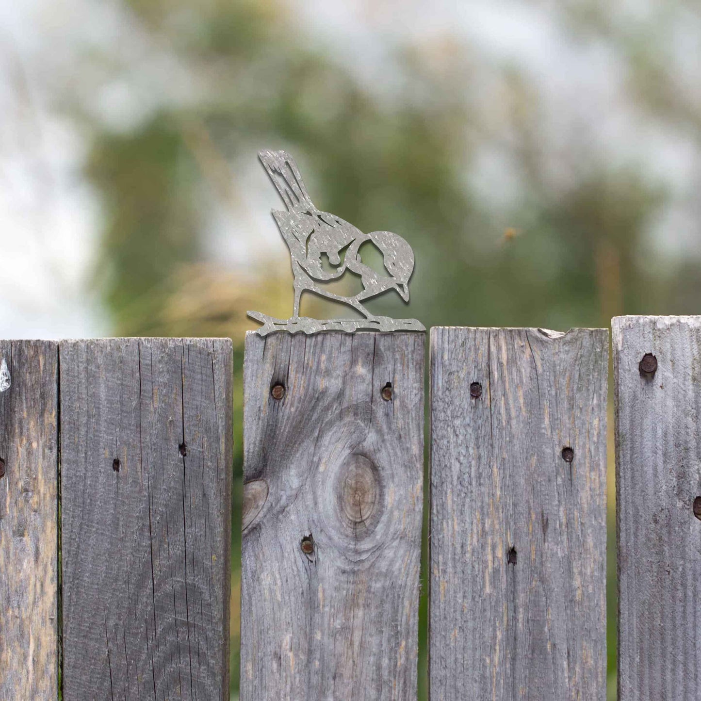 Metal garden decoration featuring a bird silhouette with a rustic finish, perched on a branch, designed to enhance fence tops or wooden posts, adding a natural and charming touch to outdoor spaces.