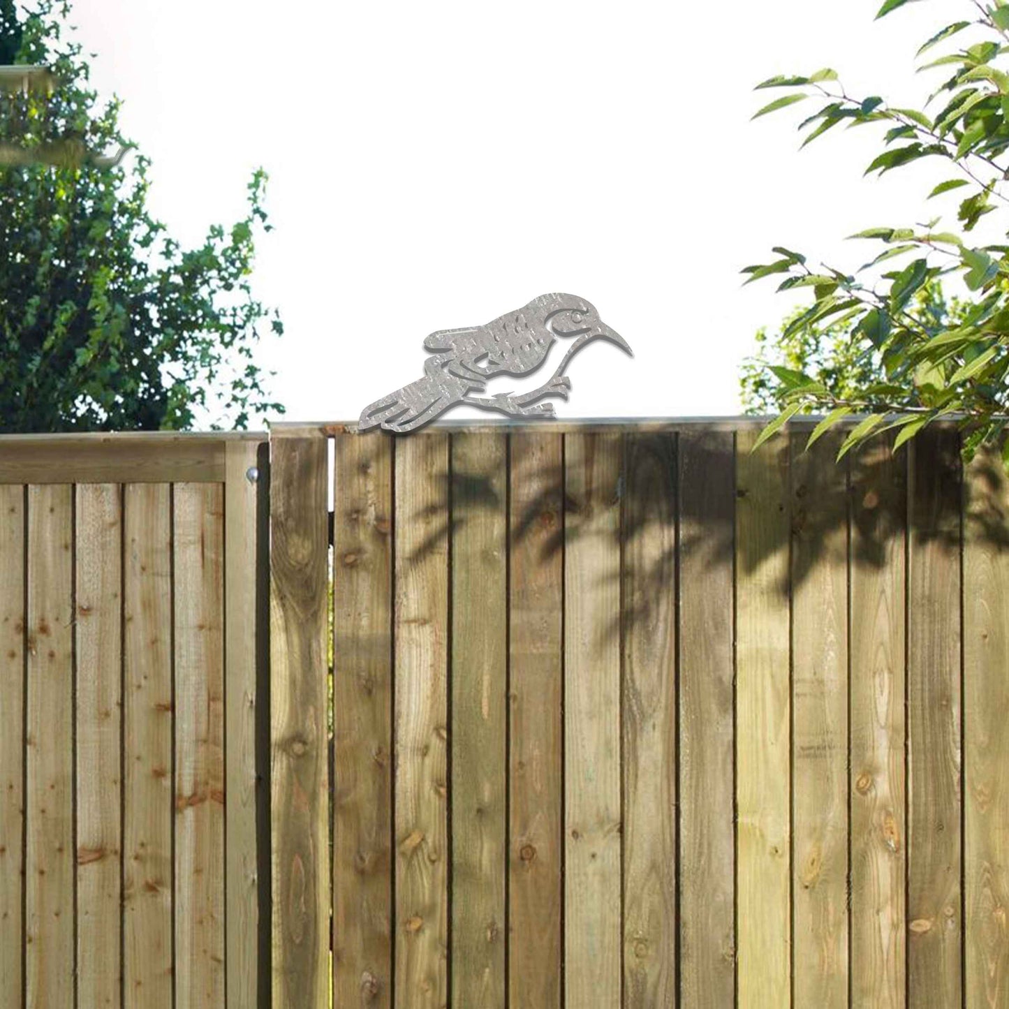 Metal garden decoration featuring a bird silhouette with intricate cutout details, adding a sleek and modern touch to outdoor spaces, designed to sit gracefully on fence posts or wooden beams.