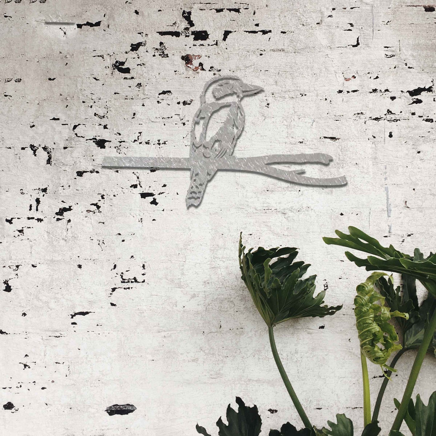 Metal garden decoration featuring a kingfisher perched on a branch with intricate cutout details and a rustic finish, designed to enhance walls or fences, adding a natural and elegant touch to outdoor spaces.