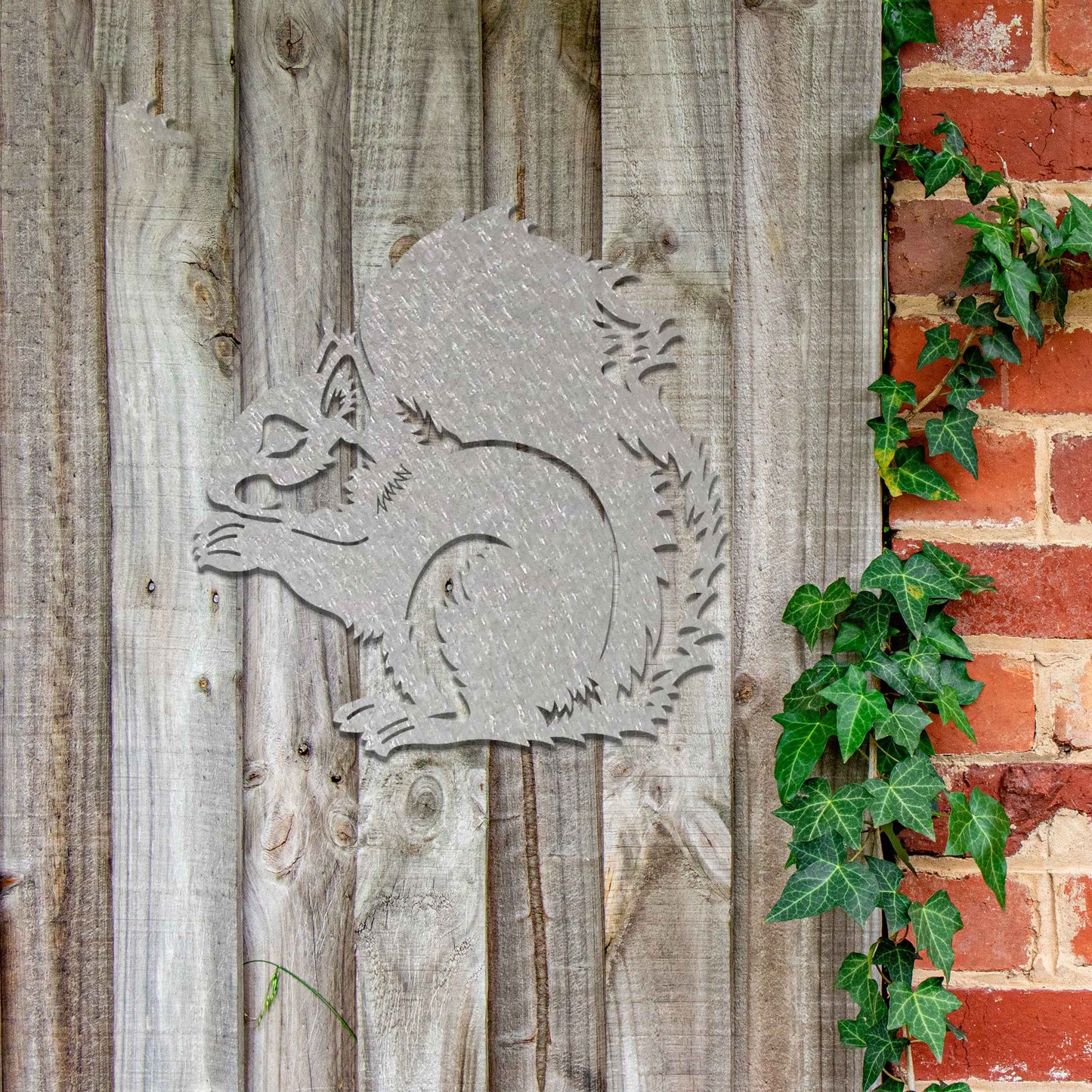 Metal garden decoration featuring a squirrel design with intricate cutout details, adding a whimsical and rustic charm to outdoor walls, blending seamlessly with natural garden surroundings.