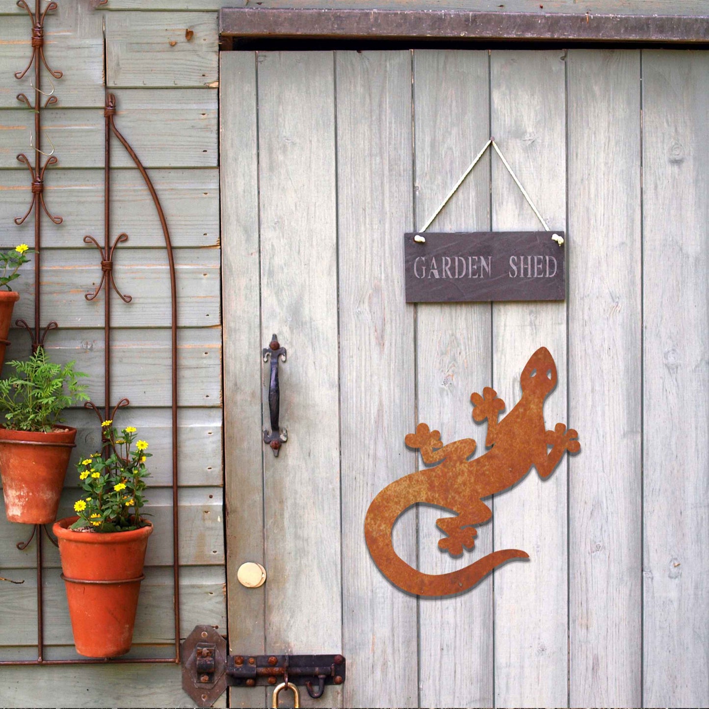Metal garden decoration featuring a playful gecko silhouette with distinct rounded feet and curved tail, adding a modern and lively touch to outdoor walls, perfectly suited for rustic and contemporary garden settings.