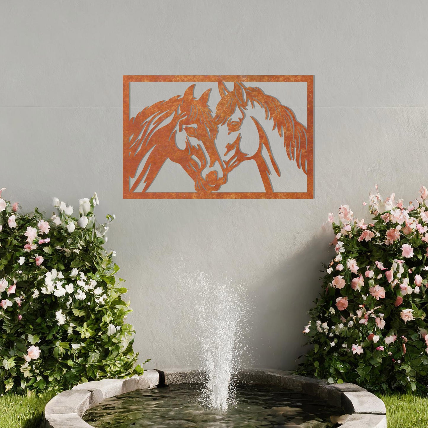 A captivating metal wall art design showcasing two horses facing each other within a rectangular frame, symbolising connection and affection. This piece beautifully complements a neutral wall in a serene and elegantly decorated outdoor space.