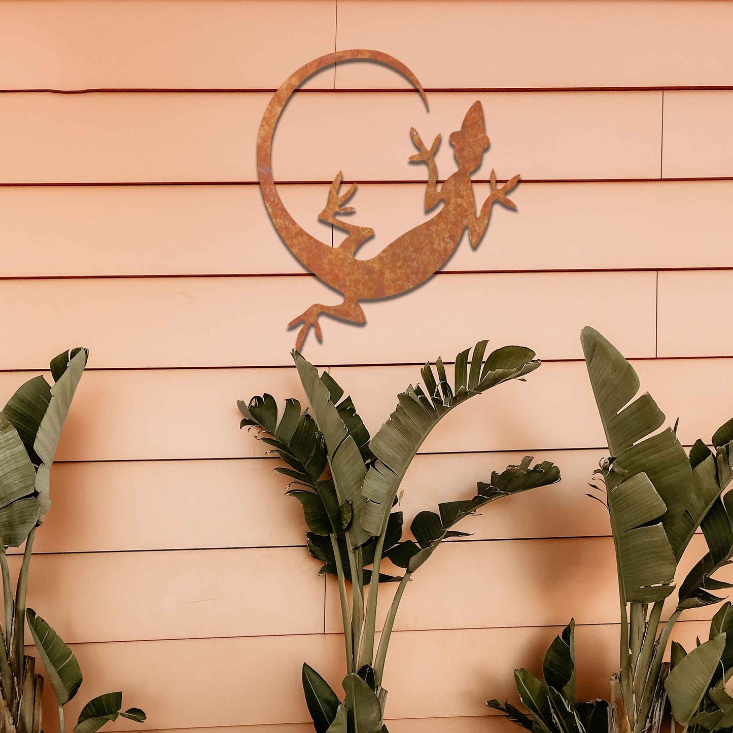 Metal garden decoration featuring a gecko silhouette design with a curved tail, adding a sleek and contemporary accent to outdoor walls, seamlessly complementing rustic and minimalist spaces.