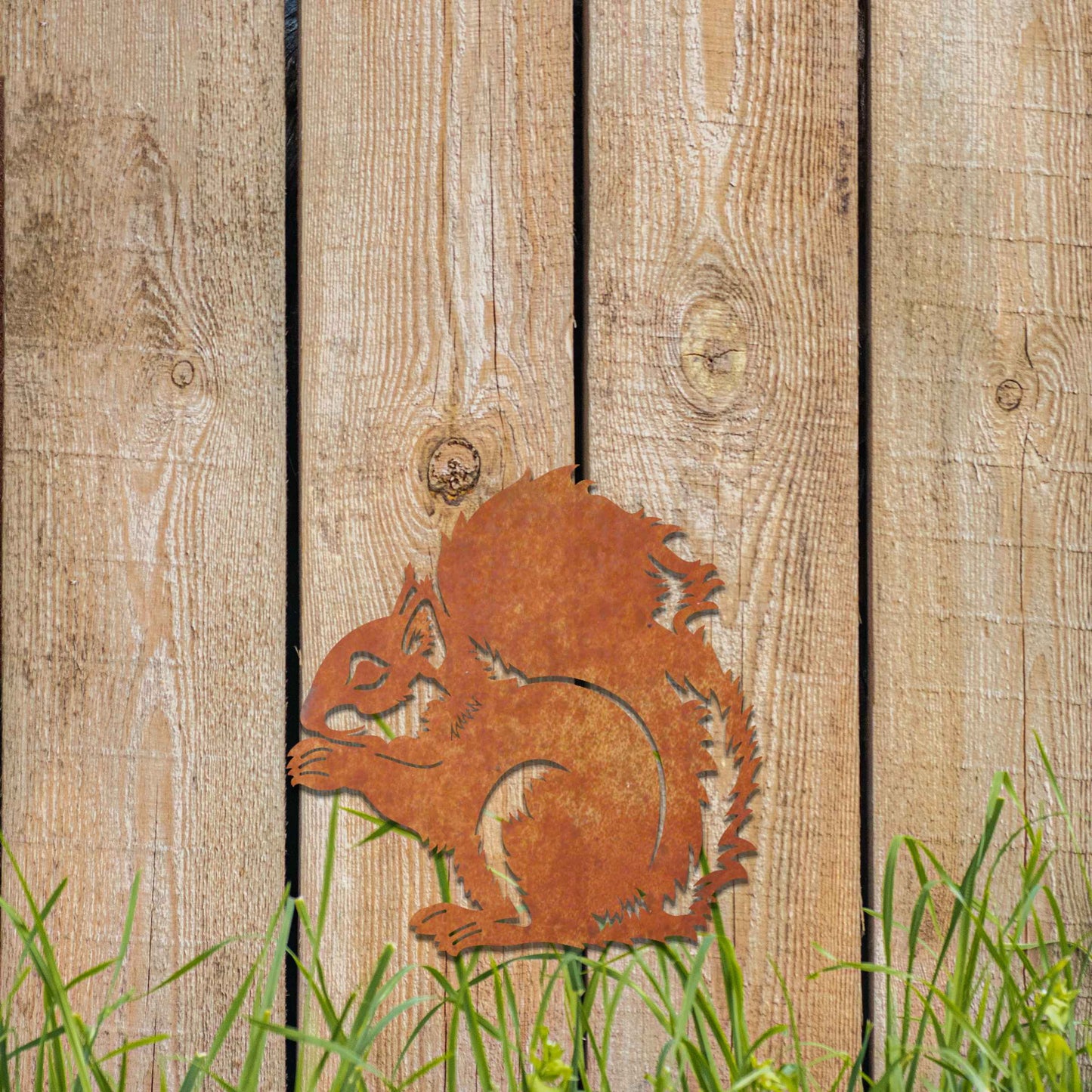 Metal garden decoration featuring a squirrel design with intricate cutout details, adding a whimsical and rustic charm to outdoor walls, blending seamlessly with natural garden surroundings.