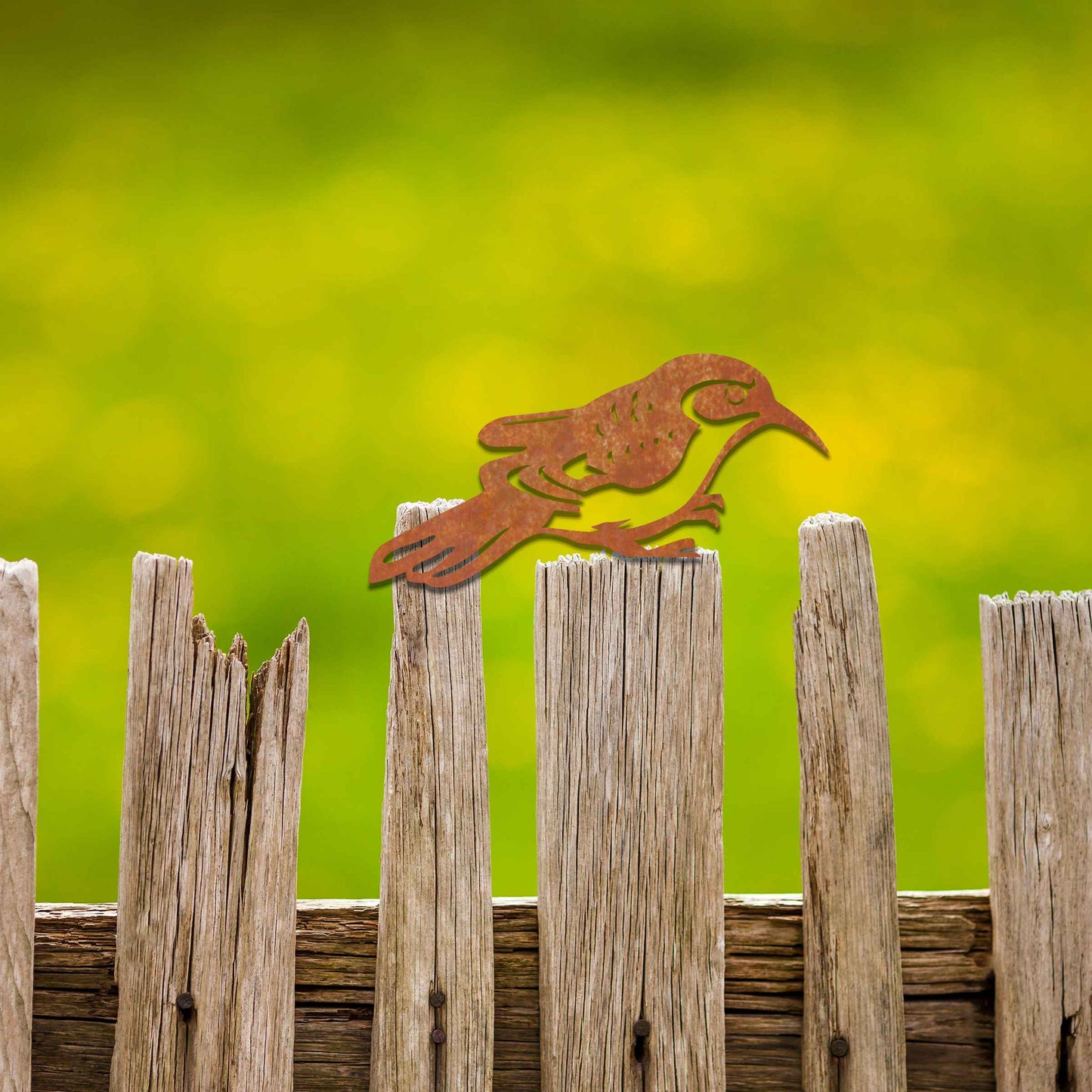Metal garden decoration featuring a bird silhouette with intricate cutout details, adding a sleek and modern touch to outdoor spaces, designed to sit gracefully on fence posts or wooden beams.