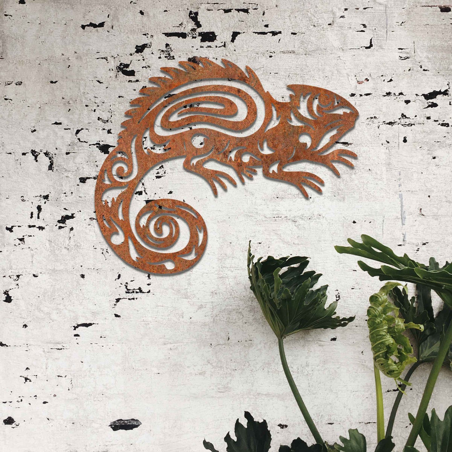 Metal wall decoration featuring a chameleon design with intricate tribal-inspired cutouts, adding an exotic and artistic touch to indoor spaces, displayed on a neutral wall in modern decor.