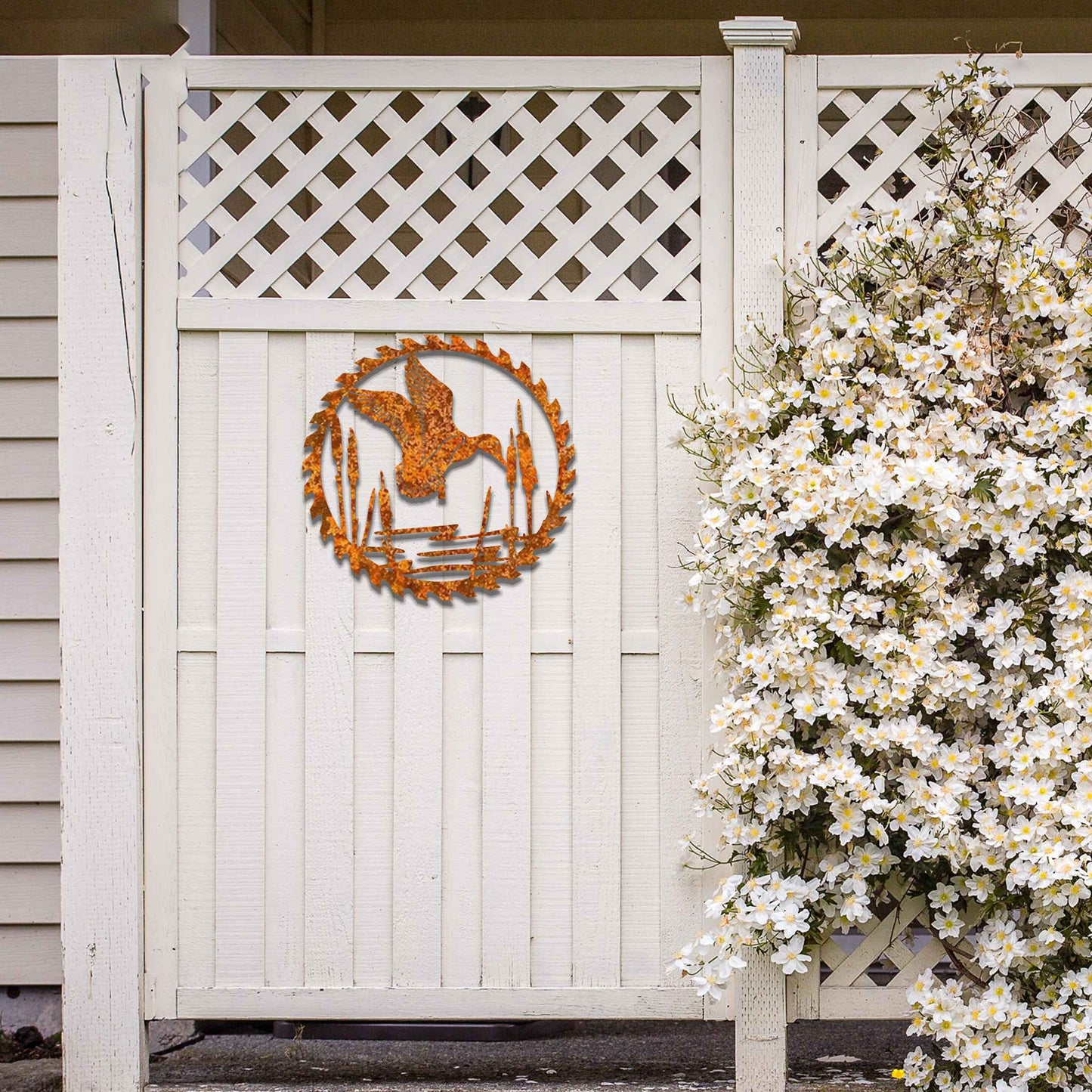 Metal garden decoration featuring a duck in flight over a pond surrounded by cattails, enclosed within a circular saw blade design, combining rustic charm and outdoor-inspired artistry to enhance garden or wall decor.
