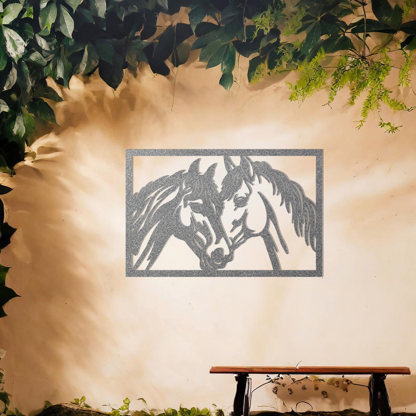 A captivating metal wall art design showcasing two horses facing each other within a rectangular frame, symbolising connection and affection. This piece beautifully complements a neutral wall in a serene and elegantly decorated outdoor space.