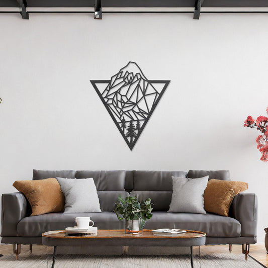Triangular wall art featuring a geometric mountain landscape design with trees at the base, evoking nature and adventure. The piece is displayed on a neutral wall in a modern living room with a stylish sofa and contemporary decor.