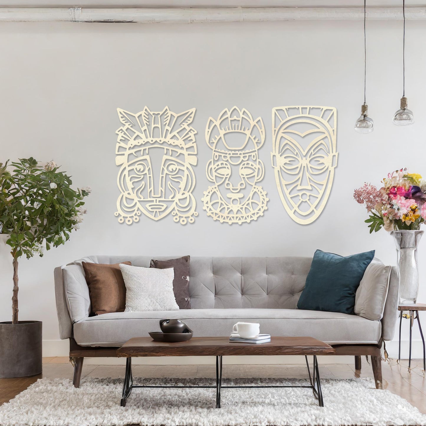 This is a wall art design featuring three tribal masks with intricate details, displayed on a neutral wall. The masks' features and patterns create an eye-catching, cultural focal point, enhancing the modern room's decor.